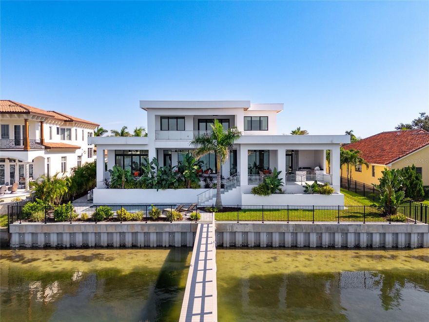 Introducing a Contemporary Waterfront Masterpiece in Tampa Bay. Striking modern architecture and clean, minimalist design come together in this extraordinary custom-built waterfront residence. Completed in 2023, this home makes a bold statement with its commanding curb appeal, soaring 28-foot entry, and dramatic 23-foot foyer. Brilliant natural light, soaring ceilings, and meticulous craftsmanship set the stage for a refined coastal lifestyle.
The open-concept floor plan highlights a chef’s dream kitchen with custom cabinetry, pearl-white quartz island, Thermador appliances, gas cooking, full-height wine chiller, and built-in espresso machine, complemented by a discreet butler’s pantry. Expansive living and dining areas open seamlessly to the water, while the executive-style office and designer guest bath add both elegance and function.
The owner’s suite is a private sanctuary with breathtaking views, balcony access, dual walk-in closets, and a spa-inspired bath featuring custom vanities, a Jacuzzi soaking tub, and a glass-enclosed multi-head rain shower. Upstairs, two additional en suite bedrooms and a large media room extend to a 330-square-foot covered terrace with commanding views of the bay.
Outdoor living is elevated with over 1,200 square feet of covered waterfront terraces, a resort-style pool and spa, outdoor kitchen, and lush landscaping. Waterfront amenities include an updated seawall, large composite dock, kayak/paddleboard launch, boat lift, and mooring capacity for a sizable yacht.
Located just ten minutes from downtown St. Petersburg and six minutes from the Gulf beaches, this residence offers an extraordinary blend of serenity and convenience. Nestled within the highly coveted, gated enclave of Bayway Isles, the community is distinguished by its 24/7 guarded security, pristine surroundings, and enduring sense of privacy.
This estate is not simply a residence but a testament to vision, artistry, and uncompromising craftsmanship. More than a home—it’s a statement of modern luxury and life without compromise. Arrange your private showing today and experience the pinnacle of waterfront living.