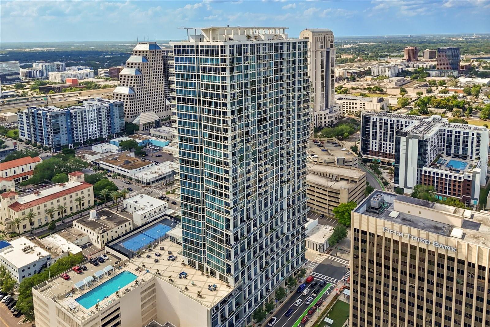 Welcome to 150 E Robinson St #2701—an extraordinary corner residence in the heart of downtown Orlando.
This 3-bedroom, 3-bathroom luxury condominium spans 2,011 square feet and showcases wrap-around floor-to-ceiling windows, framing panoramic views of Lake Eola, the sparkling city skyline, and unforgettable sunsets. From your living room, enjoy front-row views of the spectacular 4th of July fireworks over Lake Eola—an experience truly unique to this home.
Inside, modern elegance meets comfort. Gorgeous Italian ceramic tile flows throughout, while motorized electrical blinds provide effortless light and privacy control. The chef’s kitchen is a showpiece, featuring a Sub-Zero refrigerator, Thermador gas range, oven, microwave, and dishwasher, complemented by sleek quartz countertops and custom cabinetry. The open-concept design seamlessly connects the kitchen, dining, and living areas—perfect for entertaining.
The oversized primary suite is a private retreat, offering custom-built closets and a spa-inspired bathroom adorned with marble floors and walls, a soaking spa tub, and a large walk-in shower. Step out onto your private balcony to take in serene views of both Lake Eola and the city skyline. Two additional bedrooms, each with custom closet systems, provide space and comfort with access to beautifully appointed bathrooms.
This prestigious high-rise offers resort-style amenities, including a rooftop swimming pool, state-of-the-art fitness center, 24/7 concierge and security, valet services, EV charging stations, and two secured assigned parking spaces.
With its prime location, you’re just steps from Orlando’s finest dining, entertainment, and cultural destinations, as well as the scenic walking paths of Lake Eola Park.
Experience the best of luxury high-rise living—schedule your private tour of 150 E Robinson St #2701 today.