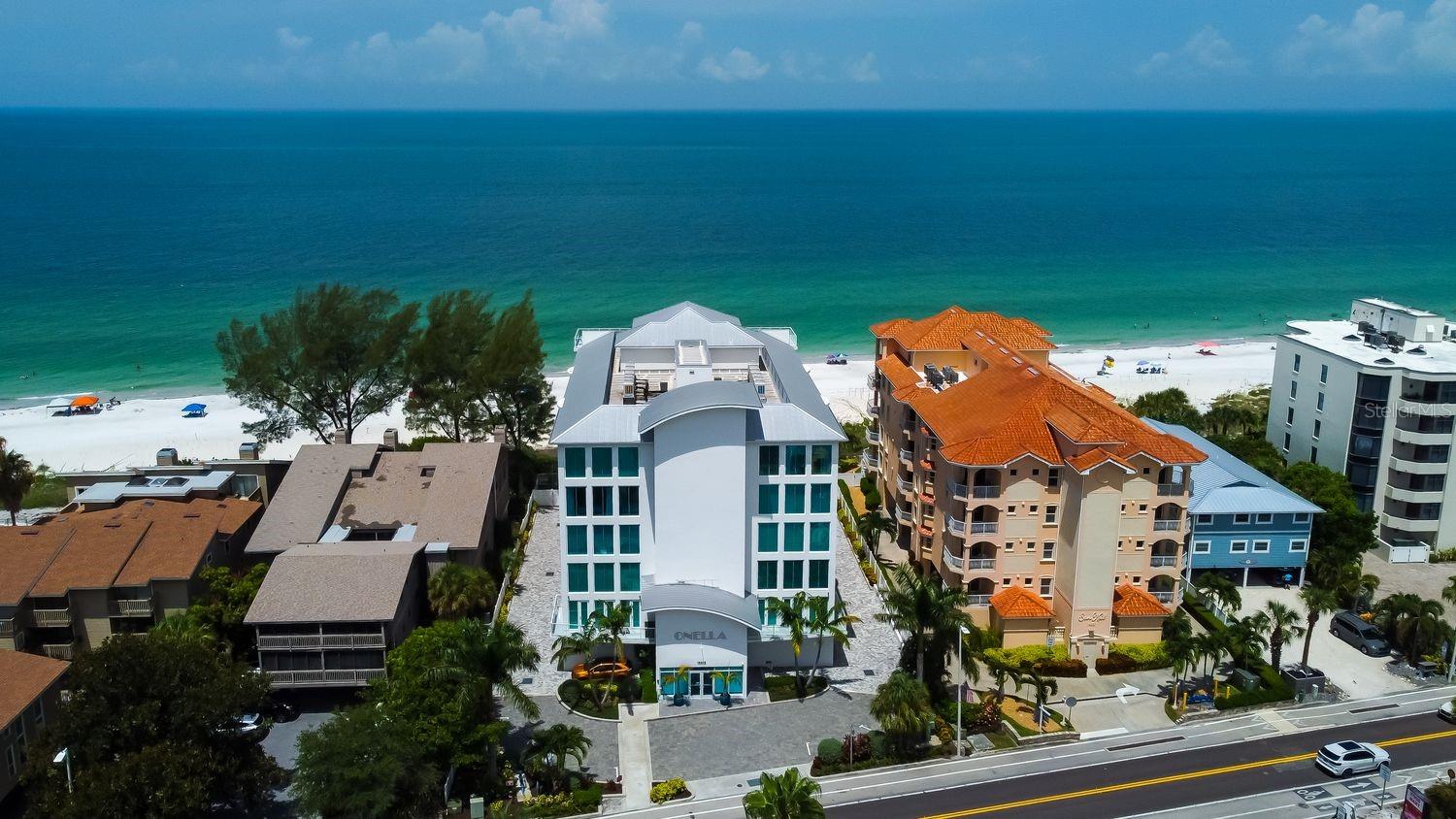 Experience unparalleled beachfront luxury at The Onella, an exclusive boutique residence built in 2018, home to just 10 distinguished estates. Here, modern elegance meets panoramic Gulf views, offering a coastal retreat that is both intimate and indulgent. This fully furnished, turnkey condo is an expansive 3,620-square-foot residence designed for those who appreciate sophistication, comfort, and impeccable craftsmanship. The elevator brings you directly to your own foyer, offering a seamless entrance into this exquisite home. From the moment you step inside, the chef’s kitchen draws you in with its sleek, contemporary design. The oversized island commands attention, inviting conversation and connection, while top-tier Sub-Zero and Wolf appliances ensure culinary excellence. A built-in bar area offers seating for seven, effortlessly blending function with style. Just beyond, the formal dining area flows into an expansive living room, where modern art and refined finishes set the tone for upscale coastal living. The real showstopper? The 700-square-foot balcony, where you’ll savor unobstructed Gulf views. Take in the salty breeze, listen to the waves, and step down your private spiral staircase for easy access to the heated pool, hot tub, and patio dining area. The primary suite is nothing short of a sanctuary. Wake up to panoramic Gulf views and step onto the balcony to feel the first light of morning. Inside, two striking accent walls add warmth and character to the space. The ensuite bath is an indulgence in itself—a freestanding soaking tub beckons for relaxation, while the extra-large walk-in shower, complete with a dual shower system and rainfall feature, creates a spa-like escape. The floating vanity with LED lighting adds a sleek, modern touch, and the California-style closet offers floor-to-ceiling storage, making organization effortless. For those who love to entertain, the bar room is a dream come true. Designed with custom cabinetry, a trio of wine fridges, and elegant finishes, this space is both functional and stylish. It’s the perfect spot to pour a glass of wine, mix a cocktail, and unwind with guests before heading out for a sunset stroll. Two additional bedrooms, each with their own ensuite bathrooms, offer a retreat for guests or family. They open onto a second private balcony, where the glow of city lights creates a completely different—yet equally mesmerizing—ambiance. Whether you’re enjoying a quiet evening or hosting overnight guests, these spaces provide privacy and comfort without compromise. This residence is designed with convenience in mind, featuring an in-unit trash chute for effortless disposal and a full water softener system for enhanced water quality throughout. The private 2.5-car garage offers secure parking and additional storage, a rare luxury in beachfront living. With direct access to world-class amenities and an exclusive, modern beachfront lifestyle, this stunning home is your rare chance to be part of The Onella.
