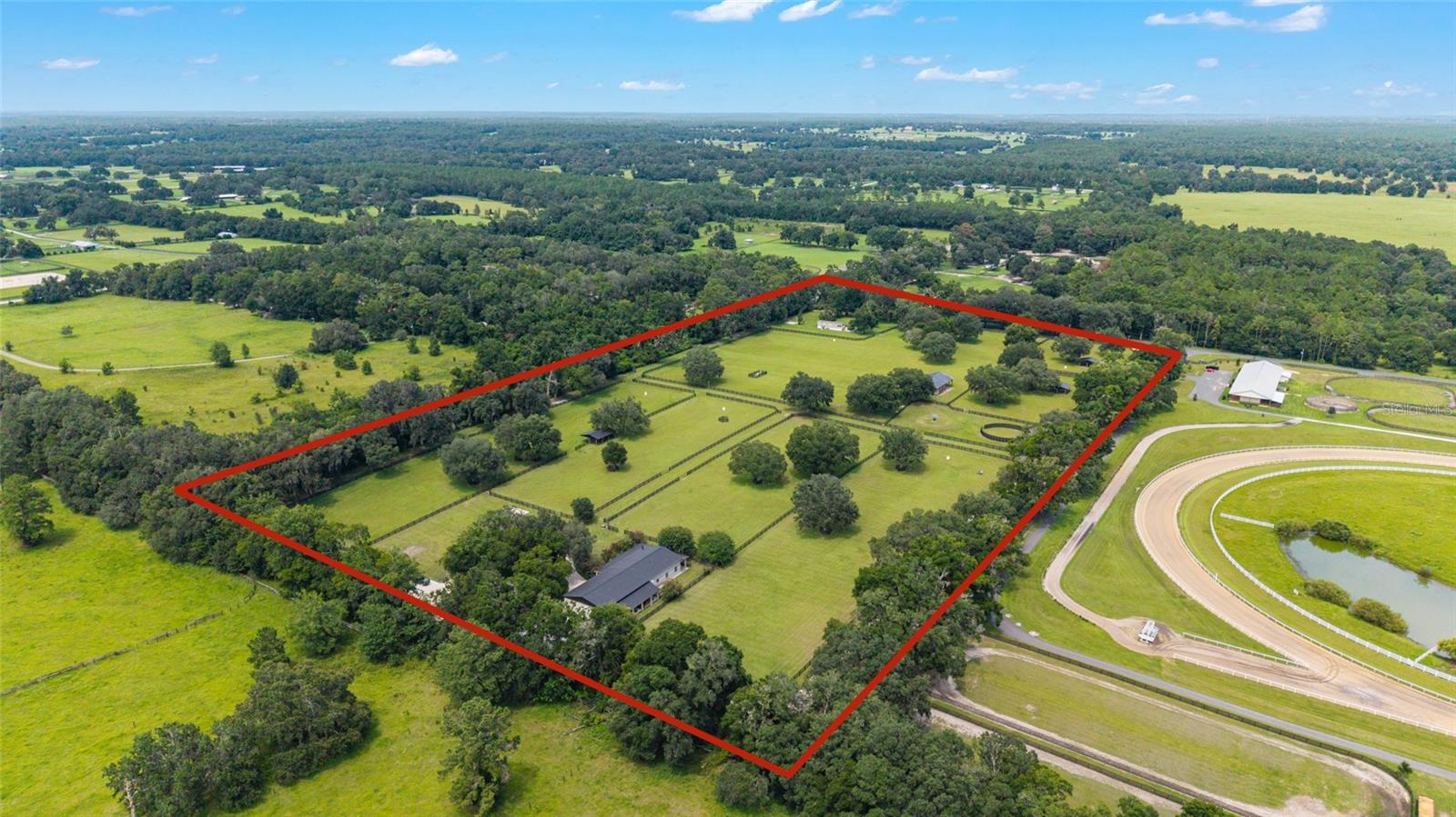 A Rare Equestrian Estate in the Heart of Florida Horse Country
Welcome to one of the most beautiful 20-acre equestrian estates in Marion County—an extraordinary property where luxury living meets impeccable equine facilities, all nestled beneath a canopy of grand oaks and soaring pecan trees. With a stunning main residence, charming guest cottage, pristine 6-stall barn, and a host of amenities, this premier estate is an exceptional offering for the discerning equestrian enthusiast.
Upon entering through one of three gated entrances, a full-length concrete drive gracefully guides you past manicured paddocks toward the main residence. Each of the nine paddocks is thoughtfully appointed with automatic waterers, double run-in sheds with integrated hay racks, and security lighting—offering both function and form for optimal horse care and safety. The 6-stall concrete-block shed-row barn along with nearby round pen and a 4-horse hot walker create a turnkey environment for equine training and activities. Wide riding lanes throughout the property allow for ease of movement and year-round riding access.
The main residence exudes timeless sophistication, offering over 2,000 square feet of refined living space complemented by expansive outdoor verandas that invite relaxation and panoramic views. The drive leads to two attached garages: a 40’ x 45’ RV-ready structure with 14’ ceilings and oversized doors—ideal for housing a motorhome, boat, or car collection—and a second, oversized 4-car garage with direct access to the gourmet kitchen.
Inside, the heart of the home is a chef’s kitchen designed for entertaining, with exquisite granite countertops, high-end cabinetry, a spacious island with seating and storage, designer tilework, and a built-in desk nook for seamless everyday functionality. Adjacent living spaces feature rich wood floors, a fireplace, French doors, and elegant architectural details that create a warm yet elevated ambiance. The wraparound veranda offers a tranquil setting for morning coffee, sunset cocktails, or hosting al fresco dinners with views of green pastures and grazing horses.
The private master suite is a sanctuary of comfort and luxury, complete with tray ceiling, crown molding, a generous walk-in closet, and spa-inspired en-suite bath featuring a jetted tub, glass-enclosed shower, dual vanities, bidet, and dedicated laundry hookups for added convenience. Two additional bedrooms, each with lighted walk-in closets and serene views, share a beautifully tiled full bath.
Located on the far side of the estate is a charming 1-bedroom, 1-bath guest cottage—perfect for extended family, staff, or guests. This 16’ x 40’ modular home features an open-concept living space, full kitchen, and private patio surrounded by manicured hedges, as well as its own gated entrance for privacy and independence.
Additional highlights include two versatile storage sheds, a concrete pad with full RV hookup, and two private wells. Positioned less than 20 minutes from the World Equestrian Center, 10 minutes from HITS, and just 5 minutes from the dining and shopping of Williston, this estate offers the perfect balance of seclusion and accessibility.
This is not just a property—it’s a lifestyle. Whether you’re a competitive or casual rider, or simply seeking a refined country retreat, this property represents an exceptional opportunity to own one of Florida’s most thoughtfully developed equestrian properties.