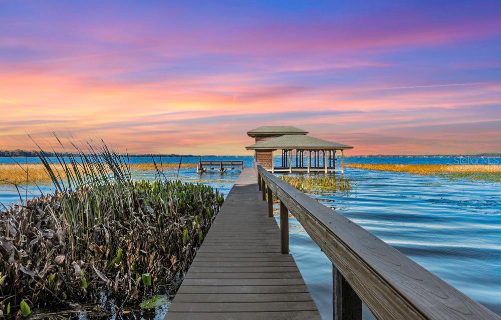 Prime Location Meets Architectural Masterpiece. This amazing waterfront opportunity sits on 1.5 acres in established SQUIRREL POINT and offers 300+ feet of Lake Dora's highly sought after SHORELINE ready with a BOATHOUSE. Lake Dora is part of Florida's infamous Harris Chain of Lakes, approximately 75,000+ acres of pure water fun and one of the best places for bass fishing with highly prized tournaments. But fishing is just one of many activities that you can enjoy from your own backyard. How about taking your boat out to the many waterfront dining options in one of the neighboring lakefront towns, Tavares being the closest approx. a 10min boat ride straight across, also lovingly called America's SEAOPLANE Capital. Or maybe you like to take friends and family for a stroll through the lovely historic downtown of MOUNT DORA with its charming lighthouse, boutiques and unique eateries. The DORA CANAL, also known as "Florida's most beautiful mile" is a narrow, winding waterway shaded by ancient cypress trees, dressed in Spanish moss. Here, time stands still as you journey through nature's artistry.
As you enter the home, the architectural mastery of this residence unfolds before you. Exquisite porcelain floors throughout the main floor lead to not one, but two living rooms to either side of the kitchen. Your eyes are drawn to the wood-burning FIREPLACE, before ascending to the COFFERED CEILINGS that reach an impressive 22 feet. In the heart of the home, the kitchen awaits with stunning WATERFALL ISLAND and QUARTZ countertops, wine fridge and ample storage. The modern design seamlessly integrates with the warm ambiance of the surroundings, offering captivating views of the LAKE. As daylight shifts, the play of sunlight through the expansive windows paints an ever-changing masterpiece.
On the main floor, the expansive primary suite features a seating area and a generously sized walk-in closet. The spa-like en-suite bathroom transforms into your private sanctuary, complete with a freestanding tub offering a picturesque view of the lake while taking a bubbly bath.
Downstairs, on the opposite side, lies a guest room with its own ensuite bathroom, a potential second primary suite. Adjacent to it, a sixth bedroom, currently serving as an office, welcomes with its elegant double doors. The third bedroom, located closer to the primary suite, offers convenience. Bedrooms four and five are nestled upstairs and share a charming, fully remodeled Jack and Jill Bathroom, perfect for accommodating family or guests. As for the loft, it presents endless possibilities—a gaming haven, a quiet reading retreat, or perhaps a space for your creative pursuits.
Back downstairs, a six-person spa awaits, almost under the stars, sheltered by an attached gazebo with chandelier that is part of the screened-in and covered patio. The opportunities for hosting gatherings and creating cherished memories in this extraordinary home are boundless with plenty of room for parking on your circular driveway and attached 3 CAR GARAGE.
Oh, the adventures are endless! Whether you fancy boating, fishing, skiing, tubing, or simply watching seaplanes gracefully touch down on their sunset flights to neighboring lakefront towns like Eustis, Leesburg, or Howey in the Hills, the world of possibilities stretches far and wide. You could even have your own seaplane here.
This is your haven. This is HOME.