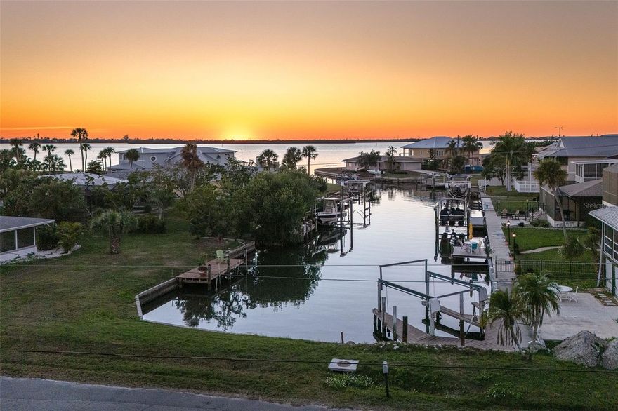Welcome to a place where every day feels intentionally slower, where sunsets paint the sky, water glimmers in the distance, and nature wraps around you like a private retreat. Set on over half an acre, this elevated coastal home offers breathtaking sunsets and tranquil water views, creating a peaceful, park-like setting that’s rare to find so close to town. Mature native landscaping, citrus trees, and open green space surround this fenced property, offering privacy, shade, and a true Old Florida feel. The main living level features a 2-bedroom, 2-bathroom split floor plan, designed for easy, comfortable living.  You will appreciate the generous living spaces all having easy care flooring, so you can spend your time enjoying life and not cleaning. Downstairs, a ground-level bonus room provides endless flexibility, ideal for a home office, gym, storage, or creative space tailored to your lifestyle. The pool area offers a huge screened lanai with a large covered area, the perfect spot for morning coffee, evening wine, or entertaining friends as the sun dips over the water.  Adding to the charm is a separate artist studio, once the working studio of renowned local artist James Sears — a truly special feature that adds history, character, and inspiration to the property. Outdoor living shines here with a heated saltwater pool, outdoor shower, chickie hut with ample room for RV or boat parking, making it easy to embrace the coastal lifestyle. Whether you’re hosting gatherings, enjoying quiet evenings, or heading out on the water, this home supports it all. A new roof, elevated construction, and thoughtful design provide peace of mind, while the location puts you just minutes from the shops, dining, and energy of Dearborn Street, and steps from Lemon Bay Park, offering trails, kayaking, and natural beauty right outside your door. This isn’t just a home, it’s a lifestyle rooted in creativity, connection, and coastal living.