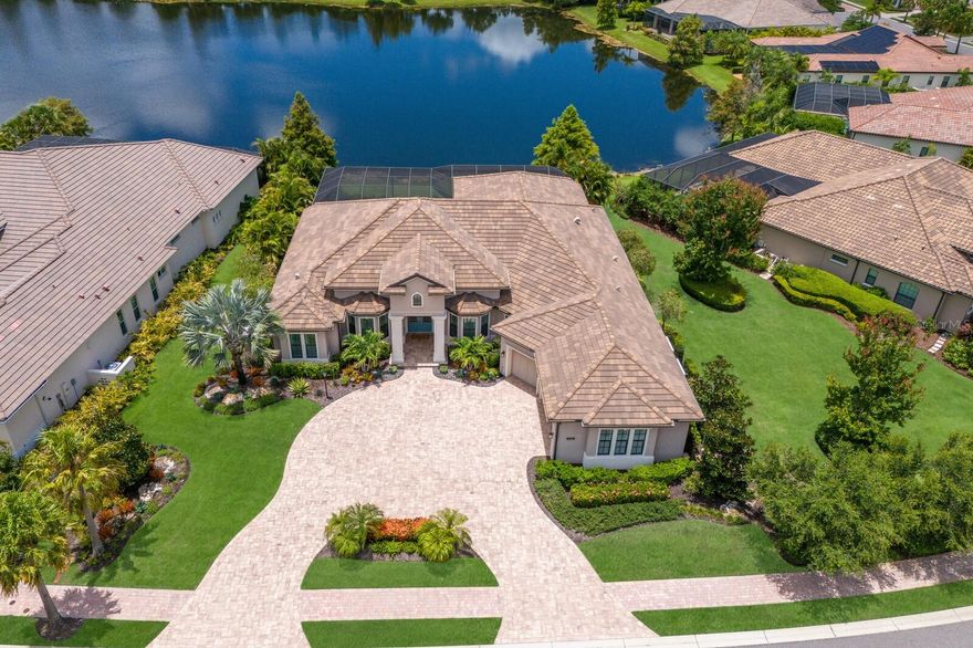 Situated on a picturesque and serene lake setting, this expanded Murano II residence in the gated Lakewood Ranch community of Country Club East showcases generously proportioned indoor-outdoor spaces, volume ceilings, IMPACT WINDOWS and DOORS, and even boasts a GENERATOR.  Widened from Lee Wetherington’s original floor plan, this four bedroom residence boasts 3,969 square feet of expansive one-story open living and a breathtaking outdoor living area with abundant open and under cover spaces, pecky cypress ceilings, travertine deck, summer kitchen, heated saltwater pool/spa, and sublime vistas.  Seamlessly connecting this resort-styled lanai to the oversized great room and dining areas are disappearing 10’ impact glass doors into 13-foot tray ceilings. 

Chefs will delight in the beautifully appointed gourmet kitchen with SubZero, Wolf and Bosch appliances, sprawling granite counters, oversized island, wood cabinetry, wine refrigerator, dovetail soft-close drawers, and an oversized walk-in pantry.  Behind double French doors off the lanai and pool bath is a voluminous bonus room with built-in desk enhanced with disappearing impact glass sliders that open to reveal the serene outdoors.  Additionally the residence offers a  study/den off the  great room with double French entry doors, bay windows and crown molding.

Relax and unwind in the elegant owner’s retreat positioned on its own private wing, offering two oversized walk-in customized closets, direct lanai access, built in feature wall, remote privacy shades, and a luxuriously appointed spa-like bath with separate vanity stations, separate make up vanity, built-in bench that hides the plumbing for a tub, and stand-alone oversized shower. Overnight visitors will be right at home in three additional generously sized guest suites, all with walk-in closets. 

Other highlights of this 5,509 total square foot residence includes a conveniently located powder room, all solid interior doors, impact windows/doors/sliders, a generator, laundry room with cabinetry, sink, and closet, an air-conditioned Florida “basement”, pavered circular driveway, and an oversized three car garage with epoxy flooring and an air-conditioning wall unit. 

Country Club East provides its residents with the privacy of gated-community living, three community pools, and fitness center, all within a renowned community infamous for its vibrant Lakewood Ranch lifestyle near dining, shopping, polo, golf, tennis, community events and still close to the UTC area, the beaches of Sarasota, and, of course, in an A-rated school district near Out-of-Door Academy and just a few miles from IMG. Residents also have the non-mandatory option to become members of the Lakewood Ranch Golf and Country Club, which offers four championship golf courses, two clubhouses, tennis, pickelball, fitness center, heated pools, full social calendar and so much more.