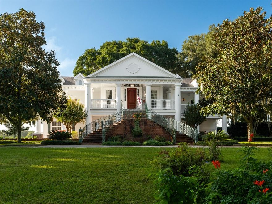 Located on 442+ acres, this remarkable property graced with elegant oak and magnolia trees offers expansive space, timeless Southern charm, and versatile living options. Ideally situated midway between Ocala and Gainesville, it’s just 8 minutes from the Jockey Club and approximately 25 minutes from the World Equestrian Center. A sense of peace washes over you as you drive through the open fields leading to the stunning two-story white Antebellum-style main residence, distinguished by its signature “welcoming arms” front entry. Inside, you’ll find 4 bedrooms, 4.5 baths, and 2 primary suites (one on each floor) with walk-in closets. The custom kitchen showcases wormy chestnut cabinetry and Carrera marble countertops. Rich cherry wood flooring flows throughout much of the home, complemented by tile and carpet in select areas. Expansive covered balconies span the upper level, with the back being completely screened, offering panoramic views of farm fields, woods, and wildlife, while matching brick patios extend below. An elevator ensures effortless movement between floors, and three fireplaces create inviting spaces throughout the home. The two-car garage with adjoining workshop adds practicality for everyday living and hobbies alike. The property also includes two additional residences, ideal for guest homes, family, or on-site staff. A true legacy estate offering privacy, beauty, and classic Southern elegance in a prime Central Florida location. Seller will consider subdividing.