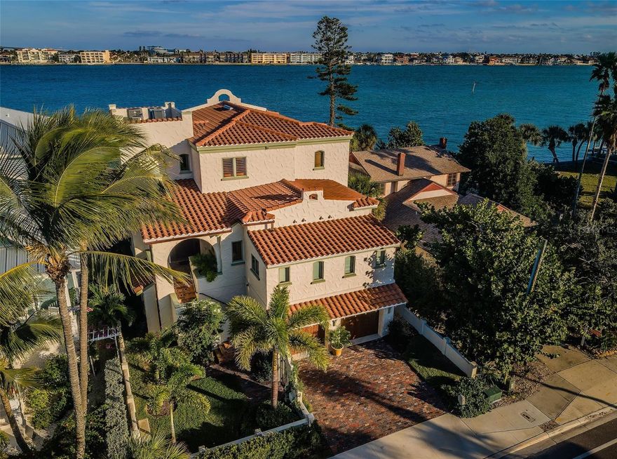 LOCATED DIRECTLY ON THE INTRACOASTAL WATERWAY IN THE HEART OF PASS-A-GRILLE, THIS LUXURIOUSLY APPOINTED ESTATE RESIDENCE HAS BEEN DESIGNED AND REIMAGINED WITH THE LOOK AND FEEL OF A DAZZLING ITALIAN VILLA! Rich custom exterior finishes, lush private landscaping and extraordinary attention to detail (inside and out) introduce a timeless waterfront experience that lives beautifully across all of its resplendent spaces. A large, private covered entry welcomes you to a home that breaths grace, sophistication and easy livability. Step into the great room and you’ll be swept away by magnificent custom woodworking and cherrywood built-ins, impressive wood-beamed ceilings, elegant cherrywood flooring, arched doorways, rounded walls, and stunning open water views. Your superb gourmet kitchen is a sumptuous culinary delight, with custom designer cabinetry, rich quartz surfaces, coastal blue tilework, Wolf & SubZero appliances, gas cooking, and a terrific island bar/prep center. Not to be outdone, the lavish matching wet bar provides a beverage chilling center and dedicated icemaker. You’ll love the butler’s pantry, with its extensive cabinetry storage and quartz counter space, SubZero refrigeration, and full-height SubZero wine chiller. Your inspiring waterfront living room features a cast stone fireplace and opens to a wide covered balcony overlooking the guest house, swimming pool and waterfront. The great room is large enough to easily contain areas for both formal and casual dining. The upper-level owner’s suite (accessible by 3-stop elevator or exquisite custom staircase), boasts his and her cherrywood closet systems with built-in dressers, and a luxurious, pampering bath with custom dual vanities, a distressed all-marble glass-enclosed rain shower, and a large soaking tub. Step out to the private owner’s balcony and enjoy miles of sweeping open water vistas – your commanding views are equally impressive, day or night. Lovely 2nd and 3rd bedrooms are ensuite with closet systems and plush full baths. 4 h bedroom has access to 4th full luxury bath and has a private waterfront balcony. Lower level has 4-car garage parking, generous storage and access to an attractive entertainment/fitness area. Overlooking the waterfront is a well-finished 450sqft covered lounging/dining deck, supported by a built-in gas cooking center. Shellstone pavers connect the deck, the Pebbletec infinity pool, a meditation garden, and the guest house. Finished in durable Pecky Cypress, the guest house is a tremendous multi-purpose space suitable as an office, den or game room, and includes a mini-kitchen and attractive full bath. Updated seawall, composite dock and 10Klb lift make for a short 5-minute boat ride to the open Gulf! Tankless HW heating, water softening/filtration, custom plantation shutters, and many, many extras. This is a rare and brilliant waterfront home in a prime location! Dimensions are estimates, buyer to verify.