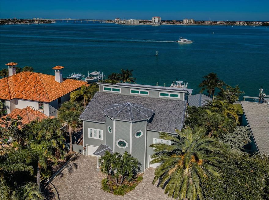 A RICHLY-FINISHED INTERIOR AND BEAUTIFULLY-MAINTAINED HOME COMPLEMENTS SPECTACULAR OPEN WATER VIEWS AND A STUNNING WATERFRONT PLAYGROUND!  A striking brick paver driveway surrounded by lush subtropical landscaping introduce a residence built for the easy living waterfront lifestyle. Soaring 32ft-high entry foyer unveils the extensive use of fine wainscoting, custom woodwork and gorgeous water views across this home’s exceptional split-bedroom floorplan.  Overlooking the water, your sizable family room opens to a 41ft-wide covered balcony with grand views of Boca Ciega Bay and the intracoastal waterway (sliding doors “pocket” into the wall, for the perfect indoor-outdoor living experience).  The impressive chef’s kitchen boasts Subzero/Wolf appliances, gas cooking, wine chiller, dazzling quartz surfaces, glass tile backsplash, white porcelain “farmhouse” sink, and a huge island bar.  You’ll love the casual dining area that overlooks the water.  Living room/den makes for an excellent theater room and is supported by a custom designer beverage bar/center.  1st living level features 2 guest bedrooms, including one that opens to the covered balcony and overlooks the water. Full guest bath is elegant with a posh vanity and superb tilework.  Upper level contains a brilliant owner’s suite that opens to a 400sqft covered balcony with commanding views of the waterfront; suite enjoys 17ft high vaulted beam ceilings and a generous walk-in closet.  Owner’s bath presents wonderful water views and is sumptuously-appointed with lavish dual quartz vanities, plush soaking tub, exquisite tilework, and a splendid walk-in glass rain-shower enclosure.  2nd upper-level waterfront bedroom is huge, opens to the upper-level deck, and includes extensive closet storage. Lower level provides large 3-car garage parking, an oversized workshop space and a multi-purpose fitness/gaming area.  Step out back and take in all that luxury waterfront living has to offer!  Spacious 400sqft covered deck transitions to a huge Pebbletec swimming pool with in-pool lounging area.  Immense paver deck supports a private hot/cold water shower and an incredible 400sqft, built-to-last gazebo! Gazebo houses a superb built-in outdoor kitchen with Wolf gas cooking, sizable beverage center, video entertainment facilities, bar seating for 5, an awning that opens over the pool, and a separate lounging/dining area overlooking the water.  Beyond the gazebo rests a substantial open area with artificial turf, walking paths, and built-in firepit seating area.  Newer seawall/composite dock (with fish cleaning station), newer 10,000 lb boat lift, and stepdown area for paddleboards.  From here, you’re just a 5-minute boat ride to the Gulf.  New roof, hurricane impact windows/doors (with few exceptions) and many extras. This is a terrific value and an incredible waterfront living experience, with easy commuting to Tampa and a short drive to the beach!  Dimensions are estimates, buyer to verify.