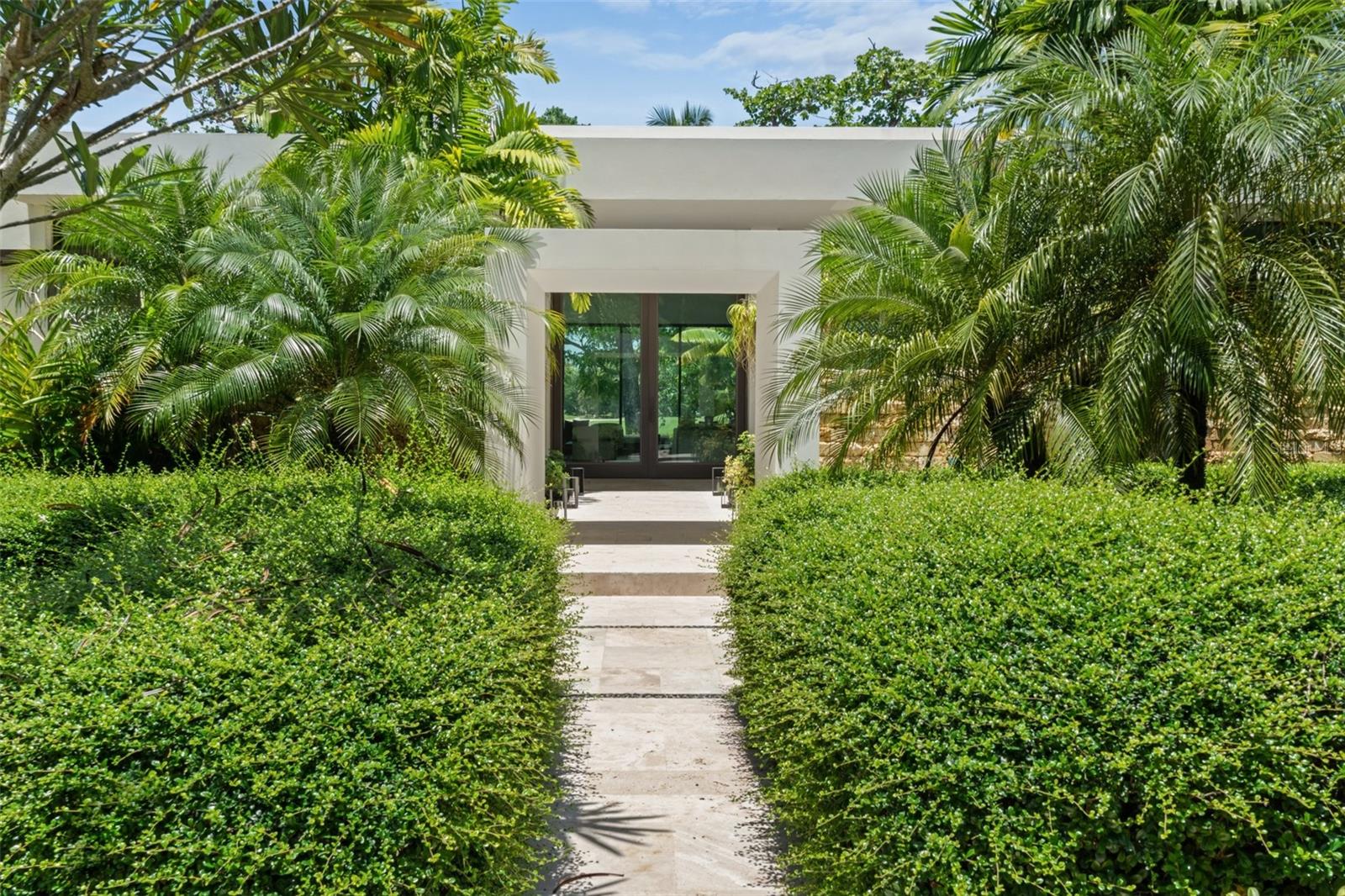 Welcome to one of Puerto Rico’s most iconic and exclusive residences, an extraordinary estate located within the prestigious community of East Beach. Nestled on a lush one-acre lot, this Ritz-Carlton Reserve–branded home represents the height of luxury living, blending resort-style design with unmatched privacy and natural beauty.
Guests are welcomed through the home’s main entrance into an open-concept central living room framed by signature walls that echo the refined aesthetic of the Ritz-Carlton. Floor-to-ceiling views of the pool and surrounding gardens create a serene ambiance, complemented by a nearby half bath. Just off the foyer, the dining room flows seamlessly to a garden terrace through expansive sliding glass doors, enhancing the home’s indoor-outdoor living experience.
The gourmet kitchen is a culinary showpiece, featuring a center island with cooktop, built-in mini fridge, and panoramic views of the pool and golf course. Adjacent to the kitchen and living room is a side entrance with a full bathroom and direct access to an outdoor shower, cold plunge, and sauna, bringing spa-level luxury into everyday living.
Each of the bedrooms is uniquely designed as a private retreat. The primary suite is a sanctuary of indulgence, showcasing peaceful views of the garden, pool, and golf course. Its spa-inspired bathroom includes a double walk-in rainfall shower that opens to a lush outdoor garden with a volcanic stone bathtub and outdoor shower. Premium finishes include his-and-hers vanities with an outdoor seating area and a built-in walk-in closet.
On the other side, accessed through the garage, is a private wing featuring an additional bedroom, a full bathroom with a separate entrance to the bedroom, a laundry closet, pantry, and additional storage. Thoughtfully designed, this wing offers privacy and comfort, ideal for visiting guests or multigenerational living.
Ideal for entertaining, the outdoor terrace boasts a fully equipped grilling station and spacious lounge areas centered around a stunning pool and jacuzzi, designed to capture the full beauty of the surrounding landscape and deliver an unmatched resort-style experience.
Perfectly positioned near the entrance to Dorado Beach Resort and steps from Spa Botánico, this property offers both exclusivity and effortless access to Dorado’s most coveted amenities.
Architecturally iconic and rich in luxurious details, this estate is more than a residence, it is a lifestyle, delivering the ultimate expression of refinement that only a Ritz-Carlton branded property can offer.