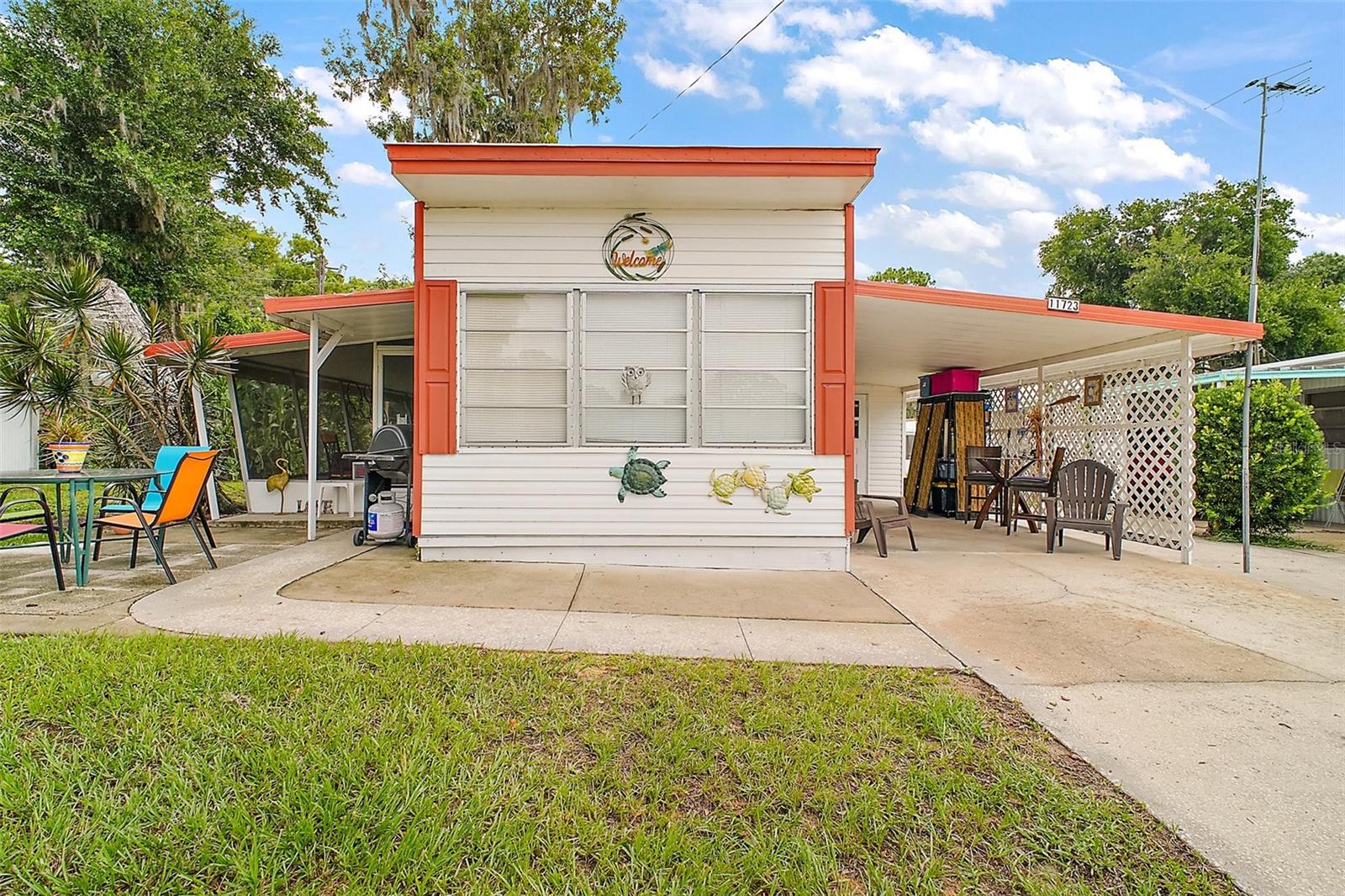 Nestled in the highly sought-after 55+ community of IMPERIAL TERRACE WEST in Tavares, this charming and cozy 2-bedroom, 2-bath home offers peaceful living in a serene setting. The home features an open-concept kitchen and living area beneath an 8-FT HIGH CEILING and is equipped with essential appliances - including a refrigerator, a new dishwasher (11/24), and an electric stove. Comfort is ensured year-round with two year old mini split systems (05/23) that efficiently heat and cool the entire home. The roof was just sealed (05/25). Two full baths, one with a tub and the other with a walk-in shower, give privacy to each bedroom. The carport and extended driveway have room for three vehicles and a golf cart. Surrounded by mature trees and lush greenery, the exterior feels like a peaceful retreat. A spacious screened-in lanai offers shaded relaxation throughout the day, while a large exterior shed/workshop adds excellent storage and workspace. This home comes partially furnished, making your move even easier. Imperial Terrace West offers a wide range of amenities: Golf-cart friendly community, Clubhouse for social events, indoor pool and hot tub/jacuzzi and a Library. There is also a marina with rentable boat slips and optional storage for boat trailers or enclosed storage trailers, adjacent to a large scenic nature preserve. With a low HOA of $25/month and the benefit that "YOU OWN YOUR OWN LAND", this home presents an exceptional opportunity for comfortable and affordable living. Schedule your tour today and discover your new home!