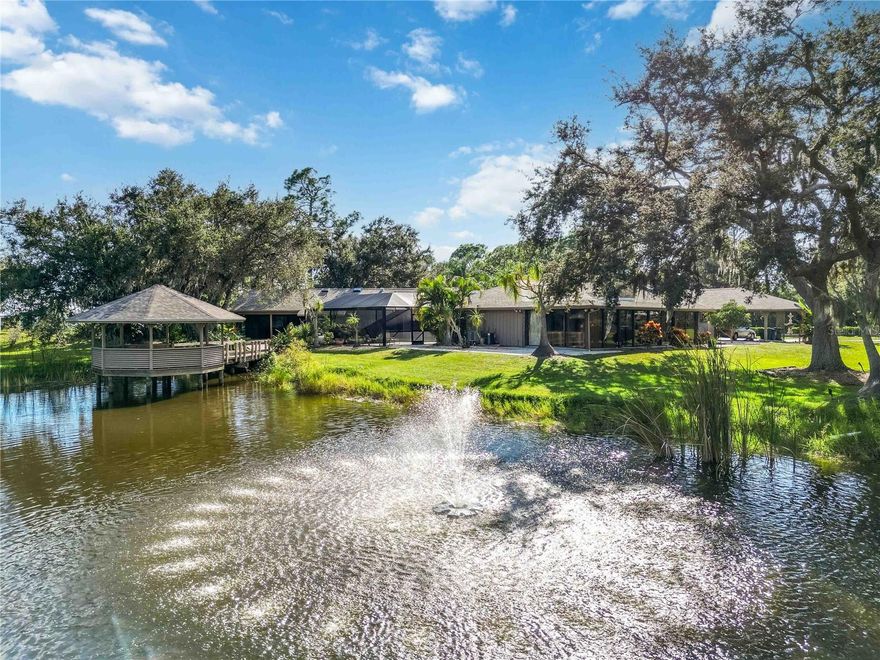 A truly rare opportunity to own a home on over 2 acres in Osprey, FL. Pine Ranch is a charming enclave of 36 properties with low HOA fees and sensible deed restrictions that offers room for your RV, boat, and space for your horses.

Conveniently positioned one mile East of US 41, within a mile of the Legacy Trail and the nationally-ranked Pine View School. Situated at the end of a cul-de-sac and bordering a protected preserve, this property offers privacy almost impossible to find West of I75 in Sarasota County. From nearly every window in the home, enjoy the views of the surrounding nature, a private fish-stocked pond, picturesque gazebo, and well-appointed pool area.

Improvements in 2025 include a new hot water heater, picture frame pool enclosure, and roof with transferable warranty. A thoughtfully designed addition expanded the original home adding a spacious primary suite featuring a vaulted ceiling, abundant natural light from multiple skylights, dual walk-in closets, a full ensuite bath, and direct access to an outdoor living space with wet bar and pool access. A beautiful library with custom wooden shelves and vaulted ceilings with a full pool bath too.

This home has a total of four bedrooms, two with ensuite bathrooms, all with sizable walk-in closets and four and a half baths. A formal living and dining room, eat in family room with a wood burning fireplace, wet bar and vaulted pecky cypress ceiling and walls, all add up to a great home to gather. The home also boasts a converted garage space which adds an additional air conditioned 500 square feet, plus a glass enclosed Florida room 555 square feet, these two areas add over 1,000 living square feet not included in the county records. Outside there is a large screened patio to truly enjoy the garden views, four car covered carport, free standing Barn/Workshop with garage door access and attached screened potting shed and a defunct pump house that could become a man cave or she shed!