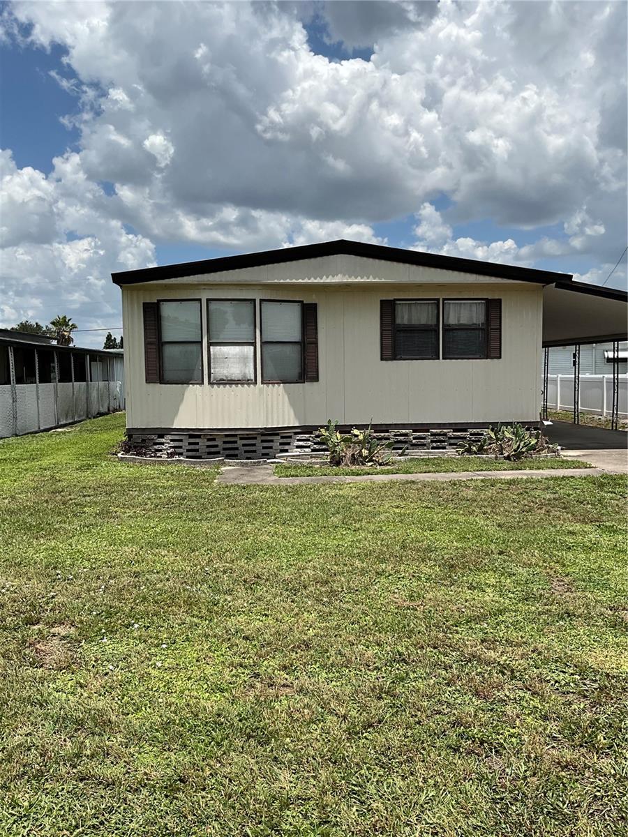 This 1056 sq. ft. single-story residence in Skyview Estates, a 55+ community located in Lakeland, Florida, offers a quaint and comfortable living space. The home features two bedrooms, including a spacious 210 sq. ft. primary bedroom, and two full bathrooms. The interior is characterized by its prominent use of wood paneling on the walls, creating a warm, rustic ambiance throughout.
The open-concept living area combines the kitchen, dining room, and living room, maximizing the use of space. The kitchen, while compact, is functional with wooden cabinetry and basic appliances. The dining area features a chandelier and built-in display cabinets, adding character to the space.
Both bedrooms are well-lit with multiple windows, offering natural light and views of the surroundings. The bathrooms are practical, with one featuring a sliding glass shower enclosure. Carpeting is prevalent in the bedrooms and living areas, contributing to the cozy feel of the home.
The living room is particularly spacious, with ample seating options and large windows that flood the area with natural light. Built-in storage solutions and window seats add both functionality and charm to the space.
Despite its modest size, this home offers a comfortable and efficient layout, ideal for those seeking a low-maintenance living situation or a cozy starter home in the Lakeland area. With very ample storage, you have an outdoor storage in your carport with your laundry facilities in it, and under the cover of your carport.
The community features a clubhouse outdoor meeting area, shuffleboard, gated community, and a fishing dock.
