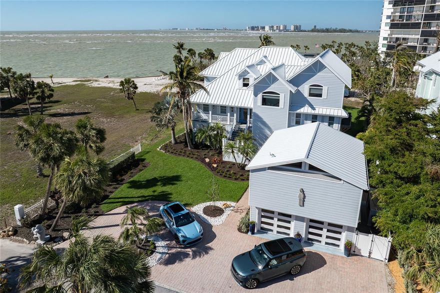 **BELOW APPRAISED VALUE**This exquisite Key West-inspired residence, perfectly positioned along Siesta Key's pristine Gulf waters, embodies the epitome of sophisticated coastal living. Spanning an impressive 4,486 square feet, this custom-built haven seamlessly blends casual elegance with luxurious comfort.

The home's grand entrance welcomes you through a covered porch into a spectacular open floor plan, where soaring ceilings and gleaming hardwood floors set the stage for refined entertainment. The great room showcases a majestic floor-to-ceiling natural cut coral fireplace, while the gourmet kitchen boasts premium KitchenAid appliances, granite countertops, and a convenient butler's pantry.

Triple pocketing glass doors create a magnificent 10-foot opening to an expansive covered balcony, perfect for enjoying endless Gulf vistas. The main level features two generously sized bedrooms, shared bath facilities, and a thoughtfully placed elevator. The upper level houses a sumptuous primary suite, complete with hardwood floors, a private Gulf-view balcony, and a luxurious ensuite bathroom. An adjoining private office with full bath offers additional Gulf views.

Outdoor living reaches new heights with a Gulf-side heated pool and spa, complemented by a 2,300-square-foot travertine patio. A mother-in-law suite provides perfect accommodations for family or visitors. Modern amenities include impact glass, hurricane protection, and a new metal roof. The low-maintenance exterior features composite siding, Trek decking, and a circle paver driveway.

Down a private, gated lane this coastal masterpiece sits moments from Siesta Key Village and the renowned Siesta Beach, while downtown Sarasota's cultural attractions lie just 15 minutes away. Recently enhanced with new pool equipment, landscape lighting, and a mosquito mist system, this residence represents the pinnacle of island living.