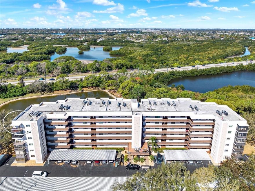 Rarely available top-floor, corner unit with stunning water views in the highly desirable Syracuse building at Five Towns! With 1,765 sq ft of living space, this spacious 2-bedroom, 2-bath penthouse features a welcoming foyer and a bright, open layout designed for comfortable everyday living and entertaining. The living and dining areas flow seamlessly into the kitchen and Florida room, where peaceful pond views create a relaxing backdrop. The Florida room opens through French doors to a screened patio, offering the perfect space to enjoy morning coffee or unwind while overlooking the water. The primary suite features a walk-in closet and an en-suite bathroom with dual vanity, a large walk-in shower, and additional storage, while the second bedroom and full bath provide comfortable accommodations for guests. Two private, tiled balconies provide breathtaking views of the Bayou and Intracoastal waters, offering tranquil outdoor spaces perfect for relaxing or entertaining. A full-sized laundry room with ample storage further enhances the convenience and functionality of this exceptional residence. An interior laundry room with extra storage is conveniently located off the kitchen. Additional highlights include hurricane-impact windows, a newer A/C system, and covered parking conveniently located near the entrance. The building also offers accessible entry with a wheelchair ramp for added convenience. Located in the highly sought-after Five Towns 55+ community, residents enjoy resort-style amenities including six swimming pools (five heated), tennis and pickleball courts, bocce ball, shuffleboard, fitness centers, libraries, billiards and card rooms, walking paths, and shaded picnic areas. Just minutes from Madeira Beach, Redington Beach, Treasure Island, Tyrone Mall, and vibrant downtown St. Petersburg, this exceptional penthouse offers the perfect blend of space, comfort, and Florida lifestyle living.