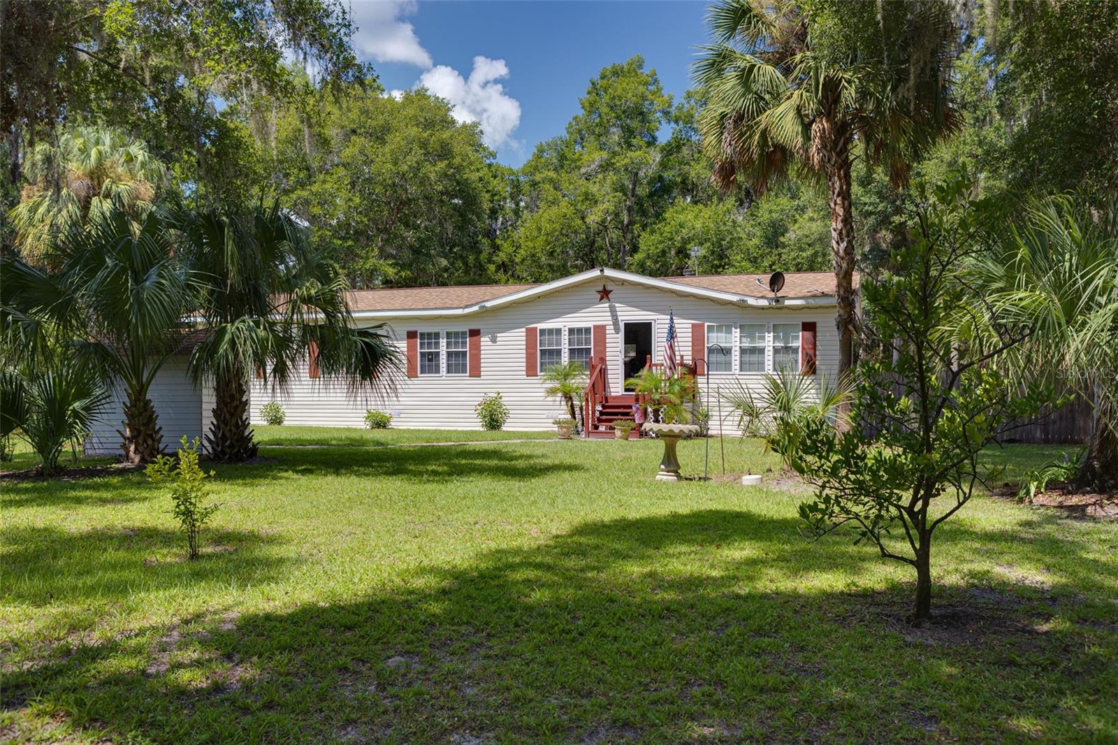 Welcome to your Country Getaway featuring a large 3-bedroom, 2-bath home with 1,836 living square feet, nestled on a generous 1.07-acre lot. Centrally located within 45 minutes to 2 hours from beaches, Orlando, and Gainesville. Lots of springs, lakes, and close to the Ocala National Forest. The open-concept layout centers on a large living room with a wood-burning fireplace, making it ideal for cozy gatherings or relaxing evenings. The eat-in kitchen features upgraded granite countertops, solid wood cabinetry, and lots of counter space with an island, perfect for meal prep and entertaining. Enjoy the outdoors? Step out onto the back deck, great for morning coffee or sunset
barbecues, and a fenced backyard that ensures privacy and room for pets or play. Motion sensor lighting is a great addition to the outdoor space. Need space for projects or storage? A separate 28X17 detached garage/workshop with an attached carport provides both. A reinforced safe room is located at the back of the garage, offering added peace of mind. Additional features include a newly installed Well House and a functional chicken coop—for anyone interested in light homesteading or sustainable living, RV Hook up, and Water Softener System. The home comes partially furnished, easing your move-in transition. The roof was replaced in 2022.
This property blends practicality with comfort—ample storage, upgraded finishes, and privacy, all wrapped in a peaceful, spacious setting. Don’t miss out: schedule your private tour today!