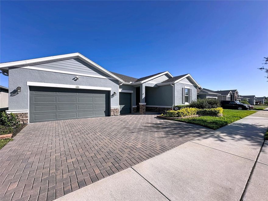 Oh what a view,! This stunning SMART home delivers 5-star curb appeal, modern upgrades, and an indoor-outdoor lifestyle designed for everyday luxury. Surrounded by stone landscape edging and lush native Florida greenery, this home invites you in with style and keeps you captivated with comfort. Step inside to a wide-open floor plan dressed in wood-look plank tile—clean, elegant, and perfect for easy living. The heart of the home is a chef-inspired kitchen featuring white wood cabinets with pullouts, pot drawers, hidden built-in trash storage, a double-size pantry, pendant lighting, quartz countertops, and a massive island ideal for serving, gathering, and entertaining. A built-in refrigerator enclosure keeps the space sleek, while a portable coffee bar adds a fun touch of flexibility for your lifestyle. With 3 bedrooms + a private den/office/craft room that easily converts to a 4th bedroom and 3 full bathrooms, there’s space for everyone. The SMART SPACE laundry suite is a true bonus, fully wrapped in cabinetry with additional storage, plus a front-load washer and dryer included. Retreat to your luxurious Primary Suite, a peaceful haven with a custom barn door, dual sinks, an expanded quartz countertop, a walk-in shower tiled to the ceiling, a frameless glass enclosure, a corner storage niche, a private toilet area with cabinetry, and a dream closet with custom built-ins. The showstopper is the Lanai, your personal sanctuary! 20' x 28' of outdoor living, finished with pavers, a partial glass enclosure, and covered protection for year-round enjoyment. You’ll love the lush butterfly garden and tranquil landscape view and a slice of private paradise, rain or shine. A 3-car garage gives you space for vehicles, hobbies, storage, and more, complete with a workbench and a garage refrigerator, both included. Energy-efficient features like dual-pane low-e windows and excellent insulation help keep utility costs low while maintaining year-round comfort. Gutters surround the entire home. Quality and comfort inside and out. This guard-gated, resort-style community offers more than just home, it delivers a lifestyle! The HOA covers cable, high-speed internet, security monitoring, and landscaping/ lawn care so you can focus on enjoying your time. At the heart of it all is the spectacular 57,000 sq ft Magnolia House, where you’ll enjoy a Member-exclusive restaurant and bar with live entertainment. Indoor/outdoor heated pools & a state-of-the-art athletic club Artisan studio, poker room, culinary kitchen, and creative spaces. Sports courts for tennis, pickleball, bocce, billiards & virtual golf,50+ active, member-led clubs for every hobby and interest. A show-stopping Event Center with a stage and professional AV setup. This isn’t just a home, it’s a lifestyle upgrade where you’ll find connection, wellness, excitement, and belonging every day. Conveniently located 45 minutes to Theme Parks, including Universal and Disney World, and Orlando International Airport, 1 ½ hours to Beaches and Port Canaveral Cruise Terminal. This isn’t just a home, it’s a lifestyle upgrade. Live your BEST LIFE at Trilogy!