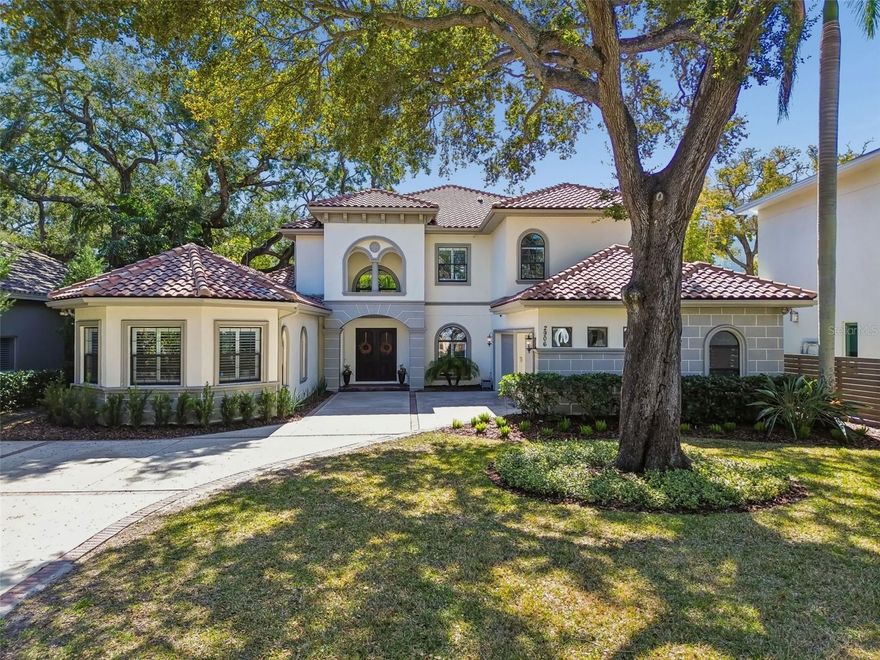 Located just four homes from Bayshore Boulevard on an 80 x 197 lot along one of South Tampa’s most desirable streets, this 2016 Bartlett Homes residence offers nearly 4,900 square feet of well-executed design, generous proportions, and exceptional natural light. The home feels expansive not only in size, but in volume, as soaring ceilings, large windows, and an open floor plan create a sense of space that is both impressive and comfortable. The main level balances formal and informal living with intention. A formal living and dining room greet you upon entry, while the central living space opens dramatically beneath 18-foot ceilings and is anchored by a gas fireplace and statement art wall. The kitchen is designed for everyday function and entertaining alike, featuring a large island with double-sided storage and seating, a gas cooktop, built-in microwave and oven, an Electrolux refrigerator, and a walk-in pantry with custom shelving and additional under-stair storage. The flow between the kitchen, living areas, and outdoor spaces is seamless. The first-floor primary suite offers privacy and scale, complete with custom shutters, a walk-in closet with built-in systems, and a spacious bath with dual vanities, a soaking tub, and a large walk-in shower with dual and rain shower heads. A secondary bedroom or office, a full pool bath, both with direct pool access complete the first level. Practical elements are thoughtfully integrated, including a mudroom with drop zone cabinetry, a full laundry room with utility sink, and a converted wine cellar now serving as additional custom storage. Upstairs, a wrought-iron staircase leads to a loft and separate media or game room, creating a natural second living area. Three additional bedrooms, all with hardwood floors, custom closets, and en-suite baths, provide privacy and flexibility. One bedroom opens to a private balcony through French doors. The outdoor living space is designed for year-round use, with a covered terrace overlooking a resort-style pool and spa, paver deck, and water features. The depth of the lot allows for meaningful backyard space, a rarity this close to Bayshore. Additional features include a three-car garage with epoxy flooring, four HVAC units, a tankless gas water heater, two electrical panels, a Rain Bird irrigation system service the home. Situated in Flood zone X, requiring no flood insurance, and high and dry during all past weather disruptions. This is a well-built, thoughtfully designed South Tampa home offering space, light, and exceptional proximity to Bayshore, downtown, Tampa International Airport, and the Gulf beaches