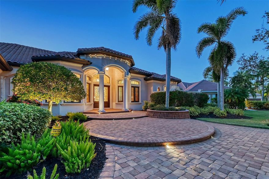 Welcome to this breathtaking Peregrine CUSTOM-BUILT ESTATE, a masterful blend of luxury, comfort, and modern conveniences. Perfectly situated on a prime WATERFRONT lot along the 16th hole of the Kings Dunes GOLF COURSE in Lakewood Ranch Golf and Country Club, this single-story home is a showcase of exceptional craftsmanship and thoughtful design. Whether you’re hosting elegant gatherings or unwinding in your private retreat, this home delivers unparalleled amenities and style. Boasting 4 SPACIOUS ENSUITE BEDROOMS plus a powder room, every detail has been curated to enhance both functionality and elegance. The primary suite is a true sanctuary, offering a tranquil escape with double-door and vestibule entry. French doors lead to the serene lanai, while the spa-inspired bathroom features a luxurious walk-in rain shower with multiple sprayers, a custom soaking tub overlooking a private garden, and dual vanities with abundant storage. Two expansive walk-in closets, a linen closet, and a cozy sitting area with French doors provide the perfect combination of comfort and convenience. Bedroom 2 serves as an ideal IN-LAW SUITE complete with bay windows that frame picturesque views of the lake and golf course, a beverage bar, exotic granite counters, built-in seating, and access to a private screened veranda. Bedrooms 3 and 4 are equally refined, featuring well-appointed bathrooms and walk-in closets. At the heart of this home lies the custom chef’s kitchen, designed to inspire culinary creativity. A large prep island with a sink, extensive quartz countertops, and top-of-the-line appliances—including a gas cooktop, wall oven, convection microwave, and Butler’s pantry—make entertaining effortless. Soft-close cabinetry with pull-outs, a separate beverage fridge, and a wine cooler add to the kitchen’s thoughtful design. The raised breakfast bar and deep composite sink complete this stunning space. The formal living room and breakfast nook showcase panoramic views through expansive aquarium windows, overlooking the lanai, second fireplace, pool, and the sweeping lake and golf course beyond. The Game/Flex Room boasts vaulted ceilings, a beverage bar, refrigerator, ice maker, and a convenient pass-through window to the lanai—perfect for hosting memorable gatherings. A versatile flex room with French doors and access to the fenced side yard offers endless possibilities. The Formal Dining Room and elegant living room, highlighted by a custom gas fireplace, further elevate the home’s calming ambiance. Step outside to the expansive lanai, where 10-foot zero-corner doors create a seamless flow between indoor and outdoor living. The fully equipped outdoor kitchen features a built-in grill, sink, ample counter space, and custom cabinetry, making it the ultimate venue for year-round entertaining. A full bar and extended covered ceiling enhance this outdoor oasis, while the sparkling pool offers the perfect backdrop for relaxation. This estate truly has it all—luxury, space, and style—set within one of the most sought-after communities. Memberships are currently available at Lakewood Ranch Golf and Country Club, providing access to two Arnold Palmer-designed championship golf courses, two additional courses, three clubhouses, fine dining, a pro shop, tennis, pickleball, a fitness center, heated pools, a full social calendar, and more. Don’t miss the opportunity to own this one-of-a-kind masterpiece.