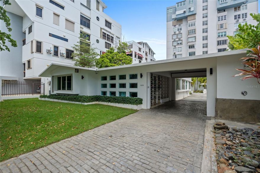 Situated on one of the most prestigious, tree-lined streets in Condado Beach, 1215 Calle Luchetti offers the rare opportunity to rent a stand-alone residence in San Juan’s most sought-after neighborhood. This exceptional property sits on an expansive lot of more than 800 sq. meters and boasts over 3,000 sq. ft. of interior living space. This fully furnished home consists of 4 bedrooms and 2 baths in the main residence, and a studio guesthouse near the pristine pool. This property provides both privacy and ample room for comfortable living and entertaining.
At the heart of the home, the open living space is perfect for friends and family to socialize. The kitchen is equipped with modern finishes including white granite countertops, durable PVC cabinetry, and a range of GE appliances, including an oven, dishwasher, and refrigerator. This space is designed to be both functional and stylish, perfectly suited for everyday use and entertaining alike. A large covered patio extends the living area outdoors, creating a generous space for dining, lounging, or hosting gatherings while enjoying the tropics.
A separate guesthouse offers additional flexibility with two double beds, a full bathroom, and a kitchenette, ideal for accommodating visitors or extended family. Outdoors, the property features a five-foot-deep swimming pool surrounded by a spacious garden and lush greenery, providing a serene oasis in the heart of the city. The lot’s size and layout allow for both open spaces and shaded areas, giving residents multiple options for recreation and relaxation.
Practical systems enhance the property’s convenience, including a powerful 30-kilowatt generator and a 500-gallon water cistern to ensure uninterrupted comfort and security. Inside, designer furnishings from Mitchell Gold, Pottery Barn, and Importadora Española contribute to the home’s modern touches, balancing sophistication and comfort.
Located just steps from the beach, fine dining, boutique shopping, and some of Puerto Rico’s top private schools, this residence offers both a prime location and a complete lifestyle. Opportunities to rent a property of this size, with a pool, guesthouse, and extensive grounds in Condado Beach are extremely limited, making 1215 Calle Luchetti a truly remarkable offering in San Juan’s real estate market.