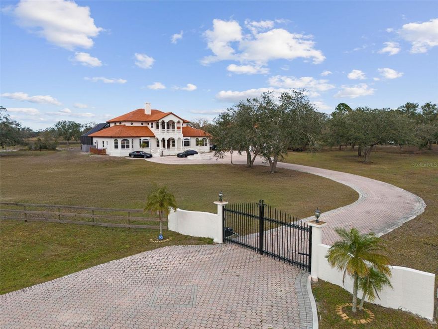 Experience a rare blend of private, resort-style living and expansive acreage just minutes from the best of Sarasota. This magnificent 10-acre estate, set behind a private gate, offers an unparalleled sanctuary for those seeking a tranquil and versatile lifestyle. 2024 Roof, 3 NEW A/C units. New Pool Cage, New Pool and equipment. The heart of the property is a stunning 6,232 sq. ft. mansion. Step inside to discover a world of refined elegance, from the grand living spaces to the meticulous attention to detail, including rare Versace tile and Italian marble accents. Designed for both grand-scale entertaining and intimate family life, the home features a massive game room, two dining areas, and a private office. The master suite is a true retreat, complete with a private living room, wet bar, and access to a secluded balcony offering a peaceful escape. The property is a dream for multi-generational living or income potential, with a dedicated 750 sq. ft. mother-in-law suite and a 1,000 sq. ft. guest house above the oversized garage, perfect for extended family, staff, or a private artist's studio. Outdoor living is an everyday escape. The expansive 3,600 sq. ft. screened-in lanai frames a truly remarkable 9-foot deep saltwater pool with a diving board and a spa that accommodates up to 12. Enjoy breathtaking views of your private lake and lush landscape from the 51-foot-long rear balcony, or watch the sunrise over your oak-lined driveway from the front balcony. This fully fenced, equestrian-friendly property includes two pastures and a luxury chicken coop, offering endless possibilities for horses, livestock, or a serene homestead. With no through traffic and minimal deed restrictions, this is more than a home—it’s a legacy property where you can live your dream life in complete privacy. Discover the ultimate Sarasota estate and make it your own.