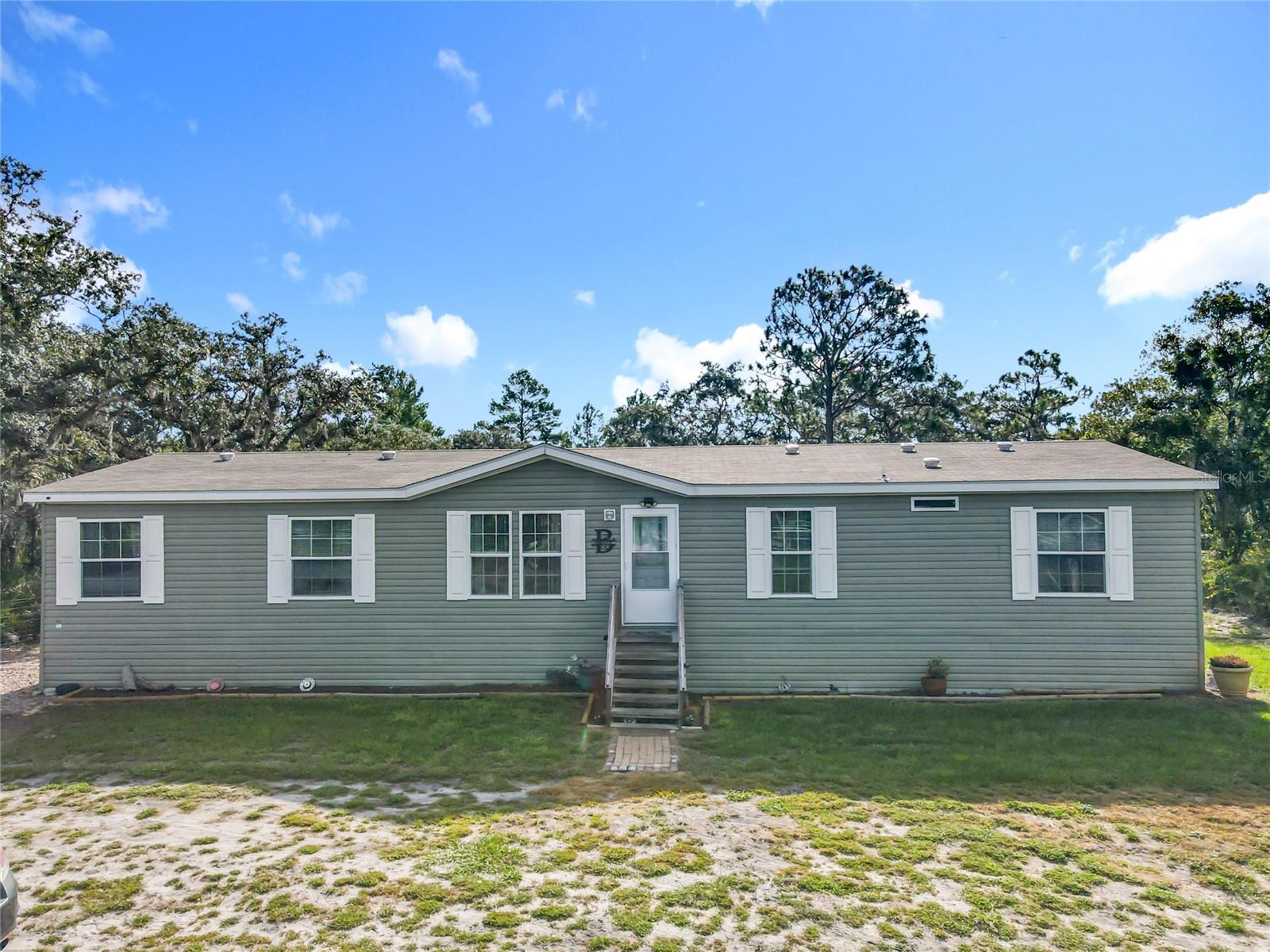 Are you looking for your own place in the country—where there's room to breathe, space to grow, and still close enough to all the essentials? Welcome to this spacious 1848 square foot manufactured home, set on a fully fenced 1.01-acre lot. Step inside and you'll find four comfortable bedrooms and two full bathrooms, along with a separate living room, dining room, and family room—giving everyone in the household their own space while still offering plenty of room to come together. The home offers a warm, open layout that’s perfect for both everyday living and entertaining guests. Whether you're hosting family dinners or enjoying a quiet night in, this home delivers the comfort and flexibility you need. Outside, the property is ready for your rural dreams. A sturdy pole barn provides great storage or workshop space, and the fenced yard offers room for livestock, pets, or gardening. It’s a great setup for anyone wanting a small homestead or simply more freedom and privacy. And while you're surrounded by peaceful countryside, you're still just a short drive to shopping, doctors, schools, job opportunities, and everything Central Florida has to offer. If you're ready to enjoy country living without giving up convenience, this is the place you've been waiting for.
