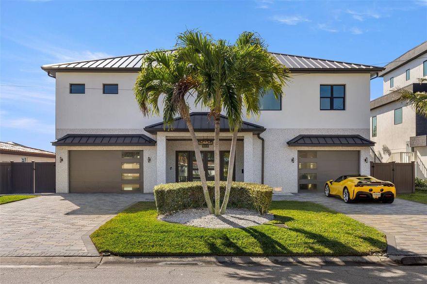 Superior construction, exceptional craftsmanship, and thoughtful design define this 2020 built custom waterfront residence. Located in the coveted Causeway Isles neighborhood, the home was built to exceed standards with solid concrete block construction, hurricane-rated impact windows and doors, metal roof, and Icynene spray-foam insulation—offering durability, efficiency, and long-term peace of mind. As a fully integrated smart home, Alexa-enabled controls enhance comfort, convenience, and energy performance throughout. The entry begins with oversized 16-foot doors, opening to a light-filled foyer anchored by a striking floating staircase. The main living level unfolds upstairs into an expansive open-concept layout with 22-foot vaulted ceilings, wide-plank oak flooring, and sweeping water views. The kitchen is a coastal statement with two-tone cabinetry, quartz surfaces, premium stainless appliances, and an oversized island centered around a farmhouse sink. The primary suite offers a serene escape, complete with water views, 10 foot ceilings, electric blackout blinds, and an enormous walk-in closet. The spa-style bath rivals a five-star resort, featuring dual quartz vanities, a large glass-enclosed shower, and a deep soaking tub. A thoughtfully designed split-bedroom layout ensures privacy and comfort for guests. The exterior is finished with stunning Tabby Shell stucco, slip-resistant pavers, a resort-style pool, covered outdoor kitchen, and ample space for entertaining. Enjoy unforgettable Treasure Island sunsets from the upper-level balcony. Boaters will appreciate the exceptional dock setup, with a 16,000-lb lift, deep protected water, Trex decking, and quick access to Boca Ciega Bay and the Gulf of Mexico. The six-car garage has tons of space for storage, work areas, and has an additional half bathroom.