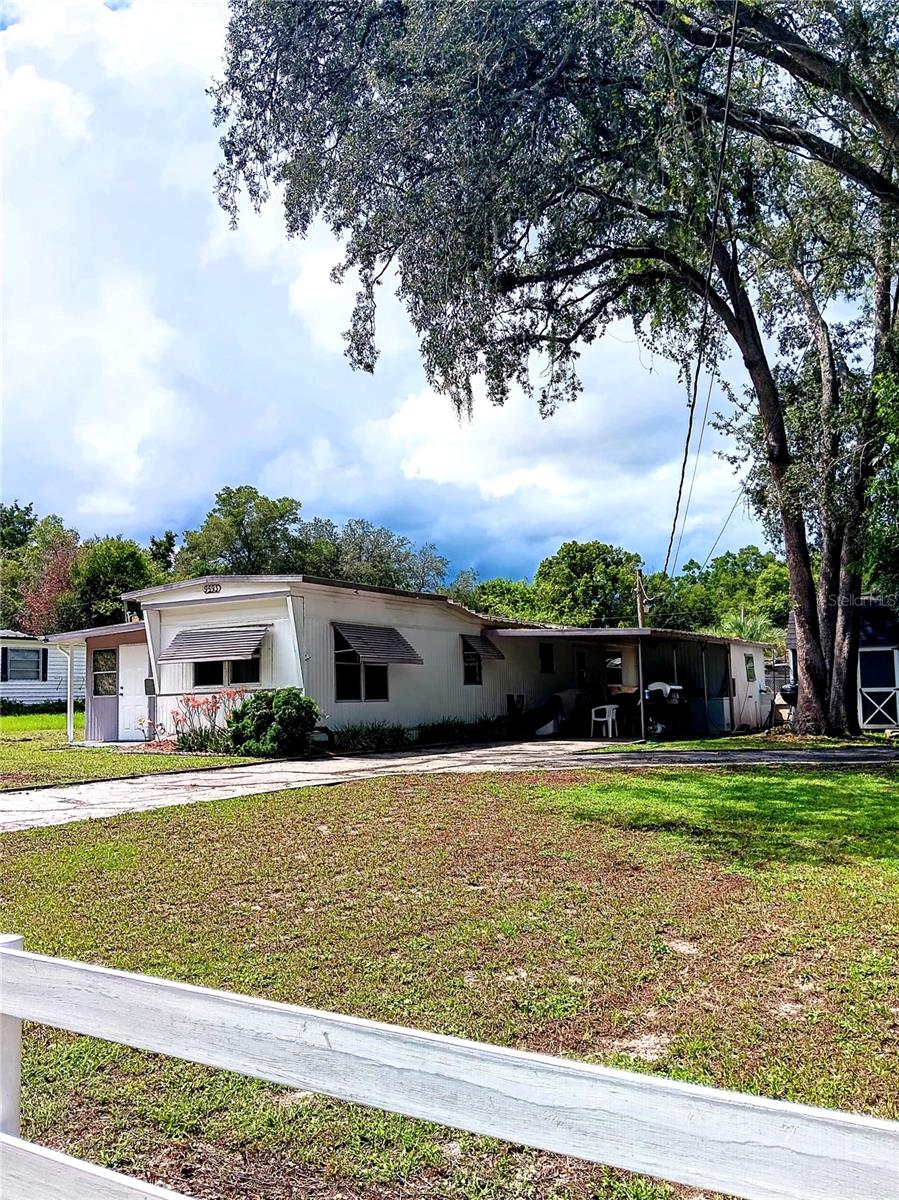 Private property. NO HOA/NO ASSOCIATION. This property is just under 1/4 acre and within 3 blocks to the Villages. Full time living, part time living, short term rental or long term rental options! Full ownership allowing for options. The addition to the single wide allows for a 3 bedroom/2 bathroom living. There is a fenced yard in the back and an hand built wood shed for extra storage. The natural firepit is an additional feature on the side of the house. Quiet neighborhood although just minutes to shopping. Excellent location, home will need some care which is expected, although in liveable condition. Popular location and private land make this a great combo for the next buyer. Interior photos available 7.12.2025