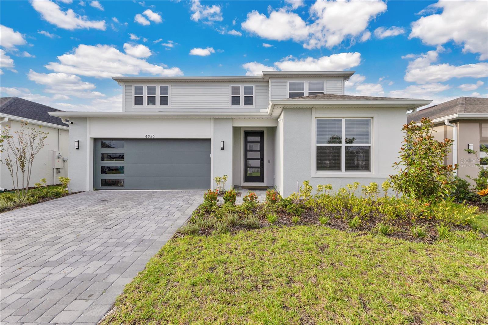 One or more photo(s) has been virtually staged. Located in Orlando’s newest master-planned community Ever Be, this 5-bedroom, 2-office, 3.5-bath, 3,777 sqft residence has been meticulously upgraded with luxury finishes throughout. The first floor features large-format porcelain tile, a gourmet kitchen with high-end KitchenAid appliances, quartz island, and abundant storage. The main living area showcases a striking stone accent wall with modern electric fireplace, while a private office on this level also includes a stone accent feature. Upstairs, new laminate flooring replaces carpet, and custom closets with built-in organizers elevate every bedroom. The master suite offers a spa-like bath with glass shower, dual vanities, and a custom walk-in closet. A garage with epoxy flooring provides parking for two vehicles inside plus space for two more in the driveway, completing the list of premium upgrades. The second floor also includes a spacious loft with a beautiful view, perfect as a family game room or private movie lounge ??. This home sits on an exclusive lake-view lot with a generous backyard ready for your dream patio design. Its proximity to the clubhouse makes it an ideal home to enjoy with family. Living in Ever Be means access to resort-style amenities such as a beach-entry pool, fitness center, splash zones, sports courts, trails, and a vibrant waterfront town center—all just minutes from Orlando International Airport, Brightline, Lake Nona, and major highways.