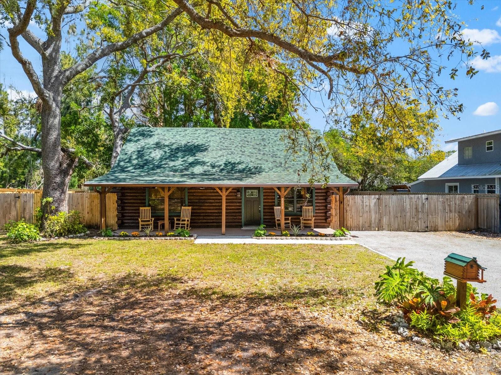 Nestled in a peaceful neighborhood, this stunning, fully remodeled log cabin is your perfect retreat to unwind and reconnect with nature. With three cozy bedrooms and two beautifully designed bathrooms, this home exudes rustic charm at every turn.
As you step inside, you’ll be welcomed by an open living area with cathedral ceilings and an inviting loft space. The cabin’s thoughtful updates shine through, from the chateau green roof that pairs perfectly with the freshly refinished brown log exterior, to the charming porch that offers a tranquil view of the surrounding trees.
Inside, the details are truly something special. The downstairs bathroom features a striking glass-enclosed log wall shower, complemented by matte ceramic tiles and a unique live edge stone vessel sink. Upstairs, the bathroom boasts calming blue porcelain tiles and paired with a rustic vanity for that perfect touch of warmth. The kitchen is a chef’s dream, with newer Frigidaire appliances, stunning veined black quartz countertops, and a spacious cooktop that makes meal prep a joy. A convenient coffee bar near the dining area is the perfect spot to sip your morning brew and start your day. Step outside and enjoy your surroundings, complete with a rustic gazebo in the backyard that’s perfect for hosting friends or just relaxing in nature. Have toys to store? No problem! The fenced backyard offers plenty of space for your boat, jet skis, or anything else you want to keep close. And with no HOA, you have the freedom to make this space truly your own. Located just minutes from the stunning Gulf Coast beaches, world-famous sunsets, fantastic fishing spots, and top-notch golf courses, this cabin offers the ultimate balance of peaceful living and adventure. Plus, Sarasota Airport is just around the corner, making travel a breeze. This home is truly a unique gem—call today to schedule a private viewing and see how it could be your perfect escape!