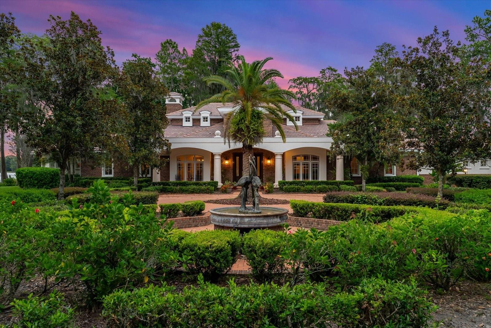Welcome to your serene retreat on Lake Hiawatha in Odessa. This elegant lakefront estate enjoys 180-degree views of one of the largest private fresh water, spring-fed lakes in Hillsborough County. Truly unique to the area, Lake Hiawatha boasts both its generous size at over 140 acres, as well as two nature preserves on the North and South sides of the lake, ensuring quiet refuge and an abundance of wildlife, including deer, otters, various bird species, bald eagles and bountiful populations of freshwater game fish just to name a few. Two freshwater springs create superior water quality and unmatched water clarity. Tucked behind its privacy gate and private entry driveway lined by beautiful crepe myrtle trees, this spectacular lakefront compound boasts over 5600sf main family home thoughtfully situated on the peninsula providing endless natural light and breathtaking views of the lake and picturesque oak trees, maples, and cypress trees.
The main house offers a top-of-the-line chef's kitchen with all Viking appliances, warming drawers, granite countertops, an oversized island with additional prep sink, and an intimate wet bar just off the hallway between the kitchen and billiard/seating room. it also features a walk-in pantry, extra refrigerator & freezer adjacent to the oversized laundry room large enough for another office or designated homework area. Truly unique, come unwind in the DOWNSTAIRS oversized primary bed and bath with coffered ceilings and large picture windows stunning southern and eastern views of the lake.
The formal dining, separate living room, and cozy office with views of the lake and a secondary covered patio for enjoying morning coffee. Two generous en-suite bedrooms upstairs also boast views of the lake and a private outdoor seating area. Just off the main home lies a detached 900sf art studio/office/gym with large picture windows overlooking the lake. Towards the front of the property there is an oversized 1300sfworkshop/garage with separate kennels & a chicken coop, along with a recently updated 2br,2ba Old Florida living cottage. At the heart of the property, enjoy an original 1910 cypress wood barn, fully restored in 2017 with cross beams, concrete polished floors, stage and lighting for live music performances, and a fabulous historic bar that runs the length of the barn. What could be better you ask, how about an adjoining outdoor bbq area with brick firepit for large gatherings with family & friends! Come enjoy the the lake views sitting on a newly constructed split-level dock with boat lifts to accommodate a large pontoon boat or ski boat, two jet skis and 2 fishing kayaks or stand-up paddle boards. Designed for entertaining and large gatherings. The property is also home to over 200 flowering trees on the grounds with azalea, gardenia, and flowering bromeliads encircling many of the live oak trees. Thinking of car collecting...bring 8 of your favorite cars to park in one of 3 garages! Full security cameras around the main home and throughout the grounds. Recent updates include new large Generac propane generator to power downstairs in 2023,. Concrete tile re-roof in 2017. Termite tent treatment to all outbuildings in 2023. Do not miss the opportunity to own your slice of paradise.