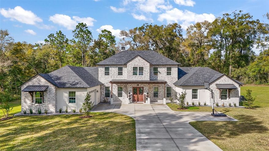Welcome to this exceptional custom-built farmhouse, perfectly situated on a private and spacious lot in beautiful DeLand. Blending timeless design with modern comfort, this home offers an elevated lifestyle both inside and out.
From the moment you arrive, you’re greeted by striking curb appeal—featuring a light brick exterior, dark architectural rooflines, and a welcoming covered front porch that sets the tone for what’s inside.
Step through the front doors into a breathtaking two-story living space, where soaring ceilings, expansive windows, and an abundance of natural light create an open and airy atmosphere. The custom staircase, complete with wood accents and classic railing, serves as a stunning architectural centerpiece, while the upper-level loft with built-in shelving adds both charm and functionality.
The thoughtfully designed layout offers spacious living areas that feel both cozy and refined—perfect for gathering, entertaining, or simply enjoying everyday life.
The experience continues outdoors with your own private resort-style retreat. The fully screened pool enclosure provides year-round enjoyment, while the covered lanai offers the perfect setting for relaxing, dining, or hosting guests. Whether you're enjoying quiet mornings or lively evenings, this space seamlessly blends indoor and outdoor living.
Each bedroom is generously sized, and the primary suite offers a peaceful escape designed for comfort and privacy.
Set in a quiet, desirable area of DeLand, this home provides the perfect balance of privacy, space, and convenience—just minutes from shopping, dining, and local amenities. 

*Showings by appointment only-Gate is closed so there is no drive by access*