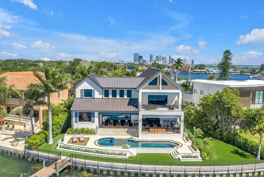 Welcome to an unparalleled resort-style estate where world-class craftsmanship meets effortless waterfront living. Custom built by one of the most renowned builders in Tampa Bay as his own personal residence, this stunning 5-bedroom, 3.5-bath masterpiece was crafted with zero compromises — every detail a reflection of what a true industry insider builds when cost is no object. Step inside to find wide-plank engineered oak flooring flowing throughout, custom oak millwork, and the signature trim work of celebrated artisan T2theS adorning every room. The gourmet kitchen is a chef's dream, appointed with thick marble countertops and a full marble backsplash, professional Wolf appliances, and a Sub-Zero refrigerator — a combination reserved for only the elite homes. The open floor plan flows seamlessly to the rear where dramatic Euro Wall Sliders — an impressive 18x10 and 12x10 — open to your own private outdoor paradise. Entertain in style from the fully equipped outdoor kitchen, unwind in the custom resort-style pool and spa surrounded by elegant travertine decking, all while enjoying breathtaking southern views. The master suite is a true sanctuary, featuring large-format Dekton slab walls in the spa-inspired bath and a custom closet with stunning glass-display cabinetry and designer LED lighting. A professional gym with built-in sauna, a distinguished parlor, and custom LED lighting throughout round out the interior offerings. From the front balcony, take in sweeping downtown skyline views that remind you of the vibrant world just moments away. Electronic hurricane screens, a full home generator, and a massive composite boat dock check every box for safety, convenience, and waterfront living. And perhaps the ultimate luxury — this exceptional estate transfers fully furnished with every piece designer-selected and curated, so your next chapter begins the moment you walk through the door. This is not just a home — this is a lifestyle.