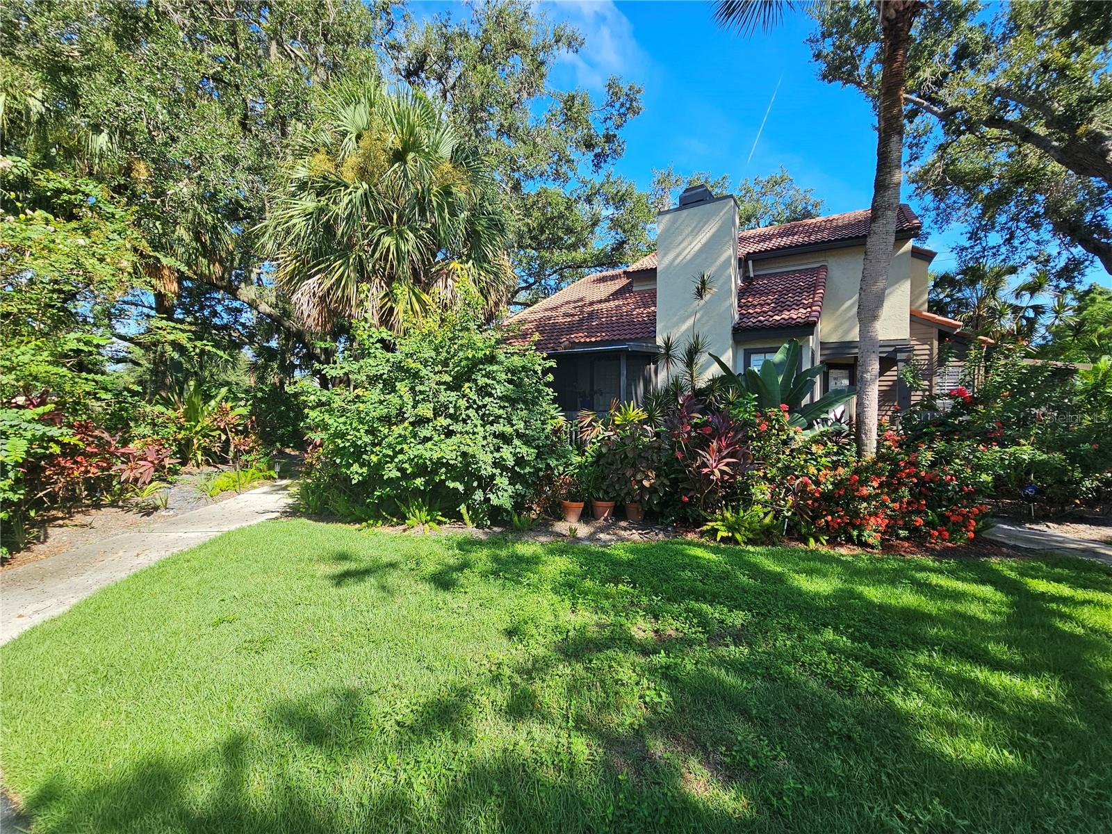 This Lakes of Sarasota 2-bedroom, 2-bathroom condominium with both a 1-car garage and a carport offers the perfect balance of comfort, convenience, and tropical charm. From the moment you step inside, you’ll appreciate the vaulted ceilings, fireplace, open layout, and luxury vinyl plank flooring throughout, which add both style and durability to the home. Natural light pours in from every angle, creating a bright and welcoming atmosphere that is further enhanced by the lush greenery surrounding the property. The wraparound screened porch provides stunning views of mature trees and vibrant landscaping, serving as an ideal space to enjoy morning coffee, evening breezes, or quiet moments surrounded by nature. This villa also features a washer and dryer for your convenience, and multiple outdoor spaces extend your living area, making it easy to embrace the Florida lifestyle. The community amenities add even more value, including a clubhouse, two pools, two hot tubs, community room, fitness room, basketball court, fishing lake and two tennis courts—all designed to make daily living enjoyable and fulfilling. With its combination of character, comfort, and a true sense of retreat, this unique home is a special opportunity to experience all that Sarasota living has to offer. Cat or small adult dog is permitted with a $300 refundable deposit, making this property as pet-friendly as it is welcoming.