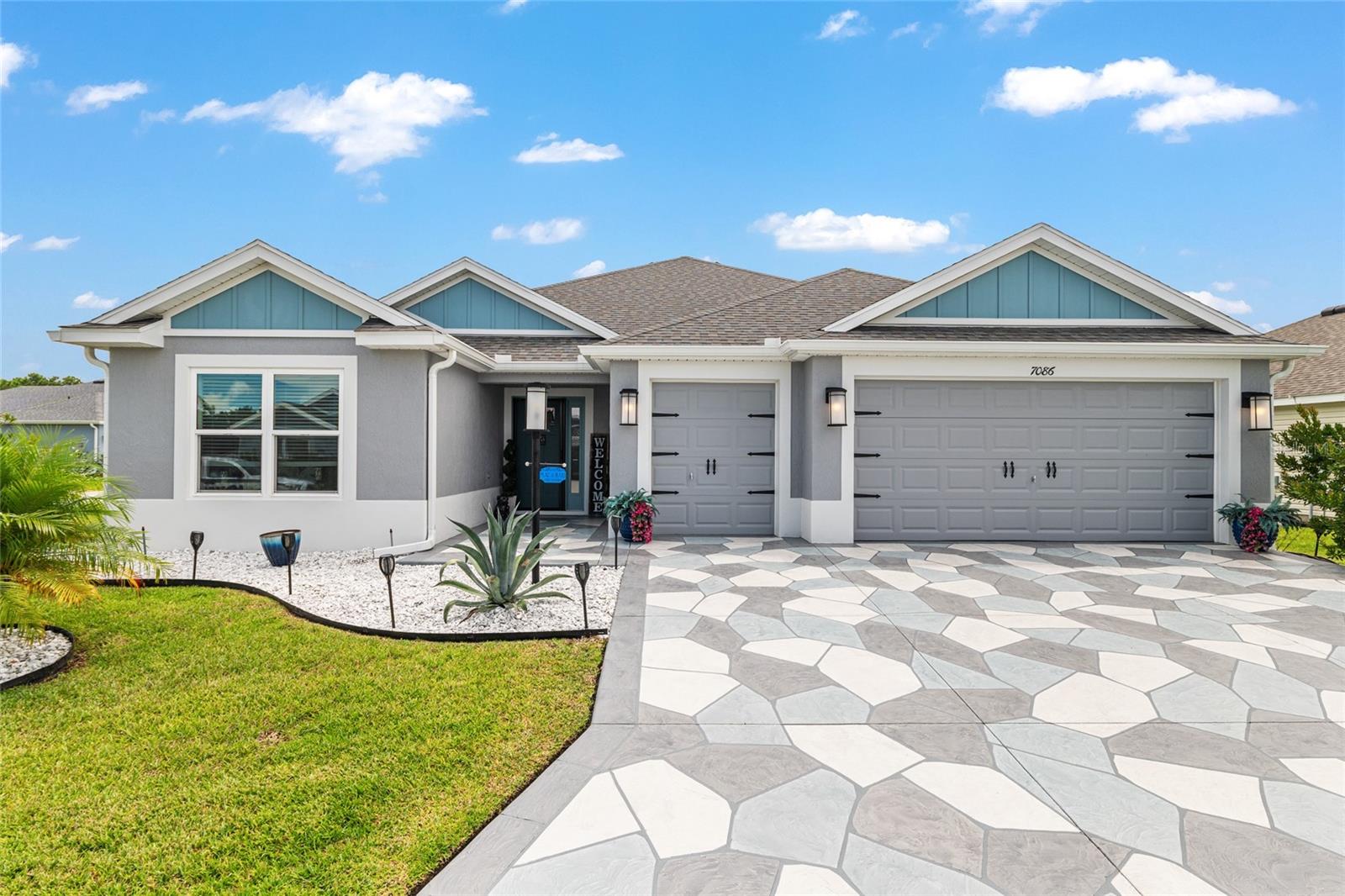 Elevate your lifestyle with this stunning corner lot 3/2 stretched Designer (Mockingbird) situated in The Village of Lake Denham, boasting endless upgrades. Constructed in 2023, it features a split and open floor plan with 1954 living SF, porcelain tile throughout, and a freshly painted interior. The primary bedroom includes his and her closets and sinks, along with a glorious walk-in shower. The kitchen sparkles with stainless steel appliances (gas stove), ample Corian countertops throughout, a sleek nook, and inside utilities. The expansive glass-enclosed lanai and epoxy-coated 2-car, plus golf cart garage, have been stretched for enhanced delight by adding an additional 3' for the lanai and 2' for the garage. The lanai features dual ceiling fans, sculptured patio floors matching the driveway, and the additional exterior patio porch makes this lanai a must-have feature. Tucked away in the garage, you will find a tankless water heater, a whole-home water system, and a wall track system to hold your gadgets. The exterior presents a picturesque appearance, reminiscent of a serene landscape painting. Enjoy the inviting palm trees, luscious grass, clusias bushes providing elegant privacy, stone beds, gutters, and relax into the night on your lovely exterior patio just off the lanai. Be sure to take a refreshing dip in the nearby Franklin Recreation Center, dance and dine the night away at Sawgrass Grove, master your putting at Mickylee Pitch & Putt, and tee off at the renowned Southern Oaks Golf Club, and explore the freshly minted Eastport Town Square. Schedule a private showing today and take the first step towards elevating your lifestyle within the friendly confines of The Villages.