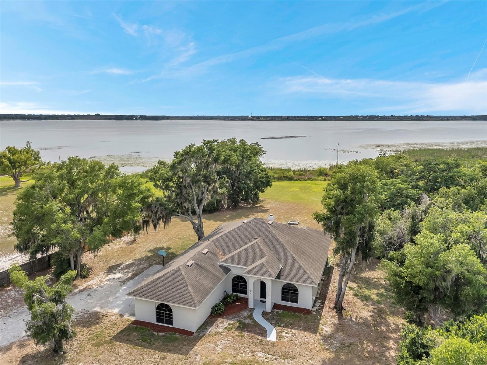Lakefront Living at Its Finest- 160 Feet of Waterfront Bliss on Lake Alfred. Experience breathtaking sunsets over the serene waters of Lake Alfred from your very own slice of paradise. Nestled on over 2.5 acres with an impressive 160 feet of lake frontage, this property is a dream for outdoor enthusiasts; bring your boat, RV, or even a seaplane! Lake Alfred spans 676 acres and offers year-round recreation including boating, swimming, and some of the best fishing in the area. Anglers will love catching largemouth bass, spotted sunfish, and bluegill, while the surrounding community enjoys lakeside playgrounds, BBQ areas, sports fields, boat ramps, and scenic walking paths. As you arrive, a private driveway welcomes you home, leading to a spacious 3-car side-entry garage and ample parking for guests and toys alike (Rvs, boats, trailers, etc). Step inside and you’ll be greeted by abundant natural light that flows effortlessly through the home’s open layout. To the right, a versatile sitting room awaits- perfect for a home office, game room, or playroom- while a formal dining room sits on the left, ready for special gatherings. The expansive living room is the heart of the home, featuring a cozy wood-burning fireplace, ideal for those rare chilly Florida evenings. The right side of the home houses three generously sized bedrooms and a beautifully renovated guest bathroom. On the opposite side, the spacious primary suite offers a tranquil retreat with its private en-suite bathroom, complete with dual vanities, a garden soaking tub, separate walk-in shower, and a large walk-in closet. Step through double French doors from both the living room and primary bedroom onto a screened patio; a perfect space to relax, entertain, or even install a hot tub (it’s already pre-wired!). Wind down your evenings by the lakeside firepit, taking in the stunning views and peaceful ambiance. The exterior of the home was painted March 2025, roof replaced in 2016 and all of the guest bedrooms were just painted and had the floors replaced (April 2025). Though you’ll feel worlds away in your lakeside oasis, you're just minutes from shopping, dining, and medical facilities. With I-4 right around the corner, you have convenient access to both Orlando and Tampa. Don’t miss this rare opportunity to own a private lakefront retreat; schedule your private tour today and get ready to call this extraordinary property your new home.