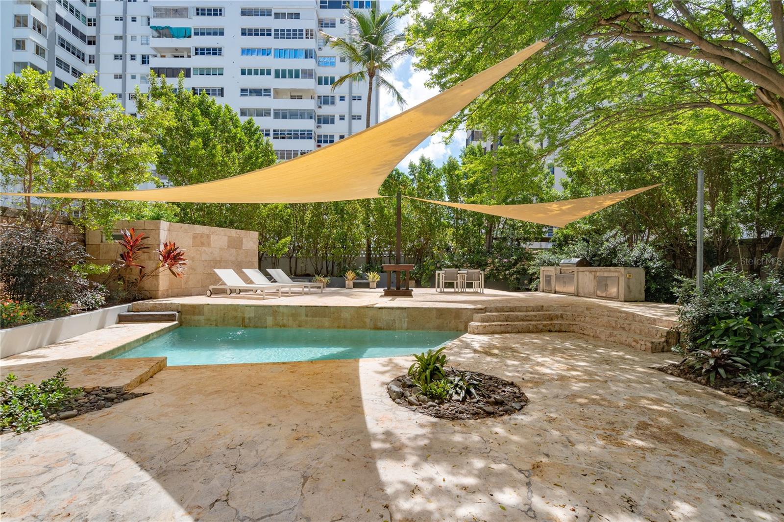 Tucked away on the quiet street, Rodriguez Serra, this mid-century modern home offers a rare blend of privacy, space, and convenience. Ideally located just three blocks from St. John’s and Robinson Schools, one block from the beach, and near top restaurants, cafés, grocery stores, and pharmacies, this property places the best of Condado right at your doorstep.
Step inside to a bright, open floor plan filled with natural light and timeless terrazzo floors. The first level features a welcoming foyer, spacious living and dining areas, and a kitchen that flows seamlessly into an exceptional private outdoor retreat.
Designed for both relaxation and entertaining, the outdoor space boasts lush landscaping, a swimming pool, BBQ area, wooden deck, outdoor shower, and abundant shade from surrounding trees and flowers.
Also on the first level is a versatile fourth bedroom with private bath, a laundry room, utility room, and convenient side entrance.
Upstairs, the primary suite includes an en-suite bathroom and walk-in closet, complemented by two additional bedrooms, each with their own en-suite bath. All three bedrooms open onto a 640 sq. ft. balcony overlooking the pool and gardens—a perfect spot to enjoy morning coffee or evening breezes.
Offering a spacious yet comfortable layout and an unmatched outdoor lifestyle, this property is a rare opportunity to own a private home in the coveted Condado neighborhood.