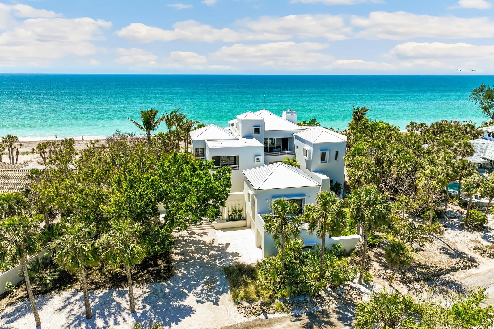 A true architectural masterpiece by acclaimed Southwest Florida architect Guy Peterson, this stunning Gulf-front estate embodies the pinnacle of coastal luxury, design, and privacy. Set on 1.06 acres with 125 feet of direct Gulf frontage and 117 feet on the Intracoastal Waterway, the residence offers unobstructed Gulf-to-Bay views and a seamless indoor-outdoor lifestyle. Boasting over 7,000 square feet of contemporary living space, the main home features 7 bedrooms—each with a private balcony—7 full baths, 2 half baths, and a dedicated home office. Expansive floor-to-ceiling windows and walls of glass flood the interiors with natural light, showcasing breathtaking sunrise and sunset vistas across the Gulf of Mexico and the Bay. The open-concept design includes two elegant living rooms, three fireplaces, and two elevators, including one in the climatized 3-car garage. The chef-inspired kitchen, fully renovated in 2020, is both sleek and functional, equipped with quartz countertops, a Viking gas range with double oven, refrigerated drawers, ice maker, and a Liebherr wine refrigerator—all with stunning Gulf views to inspire your inner gourmet. The primary suite offers a serene private retreat with Gulf views, a generous sitting area, and a spa-like ensuite bathed in natural light. Upstairs, a second living area features a wet bar and a balcony overlooking the Gulf, along with five additional guest suites and a second half bath in the office. In 2023, sleek Italian tile flooring was added, further enhancing the home’s modern aesthetic. Outdoor living is elevated with 3 screened balconies, 7 open-air balconies, an outdoor kitchen, outdoor shower, and a heated saltwater pool and spa surrounded by premium Ipe decking. A detached guest house offers complete privacy for visitors with its own kitchen, living area, bedroom, and full bath. On the bayside, a 75-foot dock with a 15,000 lb. lift platform offers instant boating access. Additional features include impact windows, electric shades, generator, ample storage, and a standing seam metal roof. Tucked within an exclusive gated community on North Manasota Key, this estate is a private, hurricane-damage-free haven surrounded by lush tropical landscaping and a privacy wall. Just steps from your own secluded beach, this is a rare opportunity to own one of Southwest Florida’s most extraordinary coastal properties.