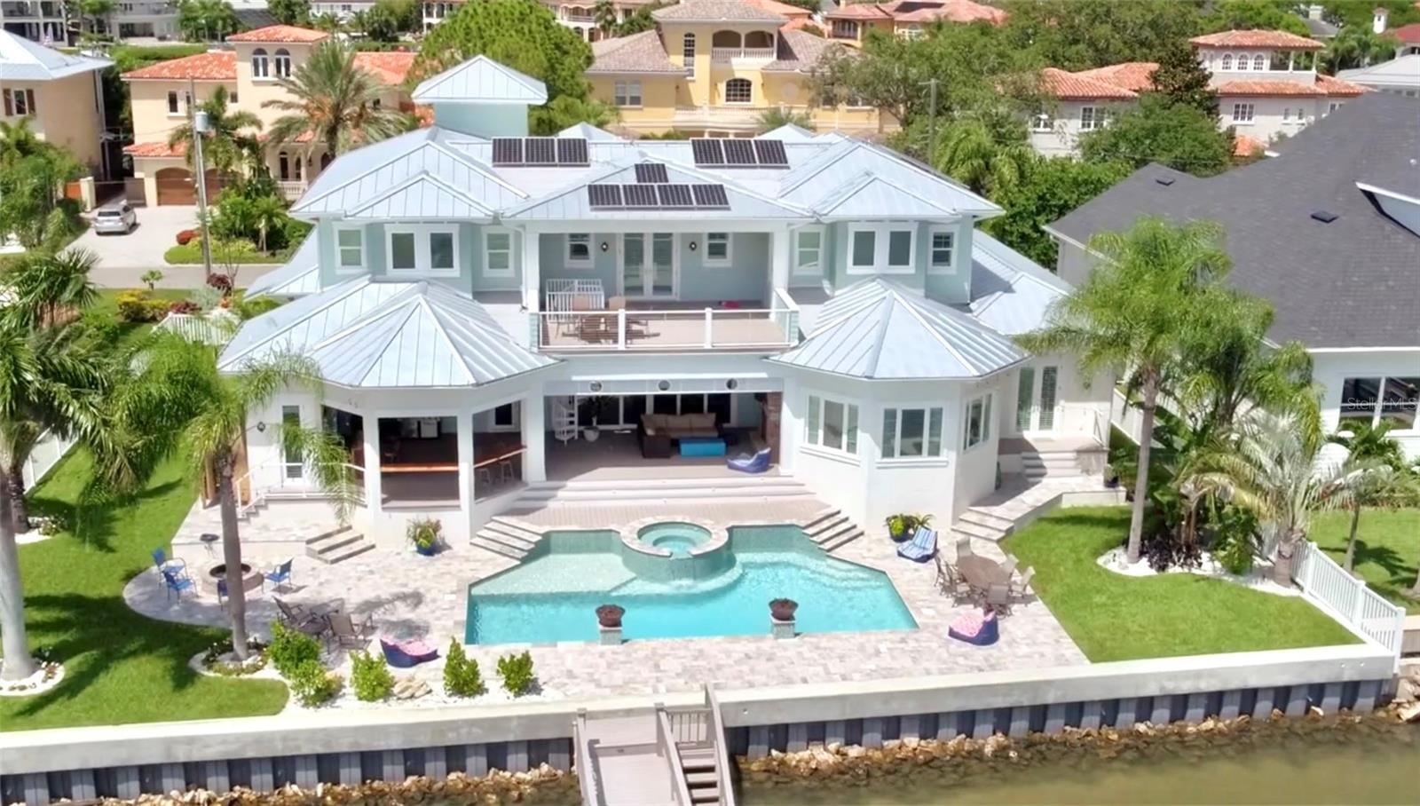 ACCEPTING BACK UP OFFERS. This Coastal/Key West style home is truly a one of a kind CUSTOM BUILD in 2017. The exterior is the most unique tabby you will ever see ... sand dollars, starfish and seahorses along with varying other shells all hand placed mixed in with a base of coquina shells and combined with hardie planks to finish off the island vibe! Interior space is perfectly designed for the best active family lifestyle. 5 en-suite bedrooms plus 2 half baths and a tiki shower! Open water West view gives the most incredible sunsets in all of Tampa from 2 large deck/lanais and from the living space inside the home. High ceilings, high end European Oak wood floors throughout, beautiful REAL Chicago brick arch, behind oven and the outdoor fireplace wall as well. Primary bedroom on the first floor has a gorgeous walnut ceiling and a huge spa-like bathroom with a soaking tub and steam shower. Ships galley door entrance to the office, 3 level elevator, new massive dock with boat and jet ski lifts PLUS a built in 10 x 10 hammock! Two 2 car garages (part of one used for storage with side garage door to take the toys out to the bay! Tubes, paddleboards etc ... Too many features to mention all -