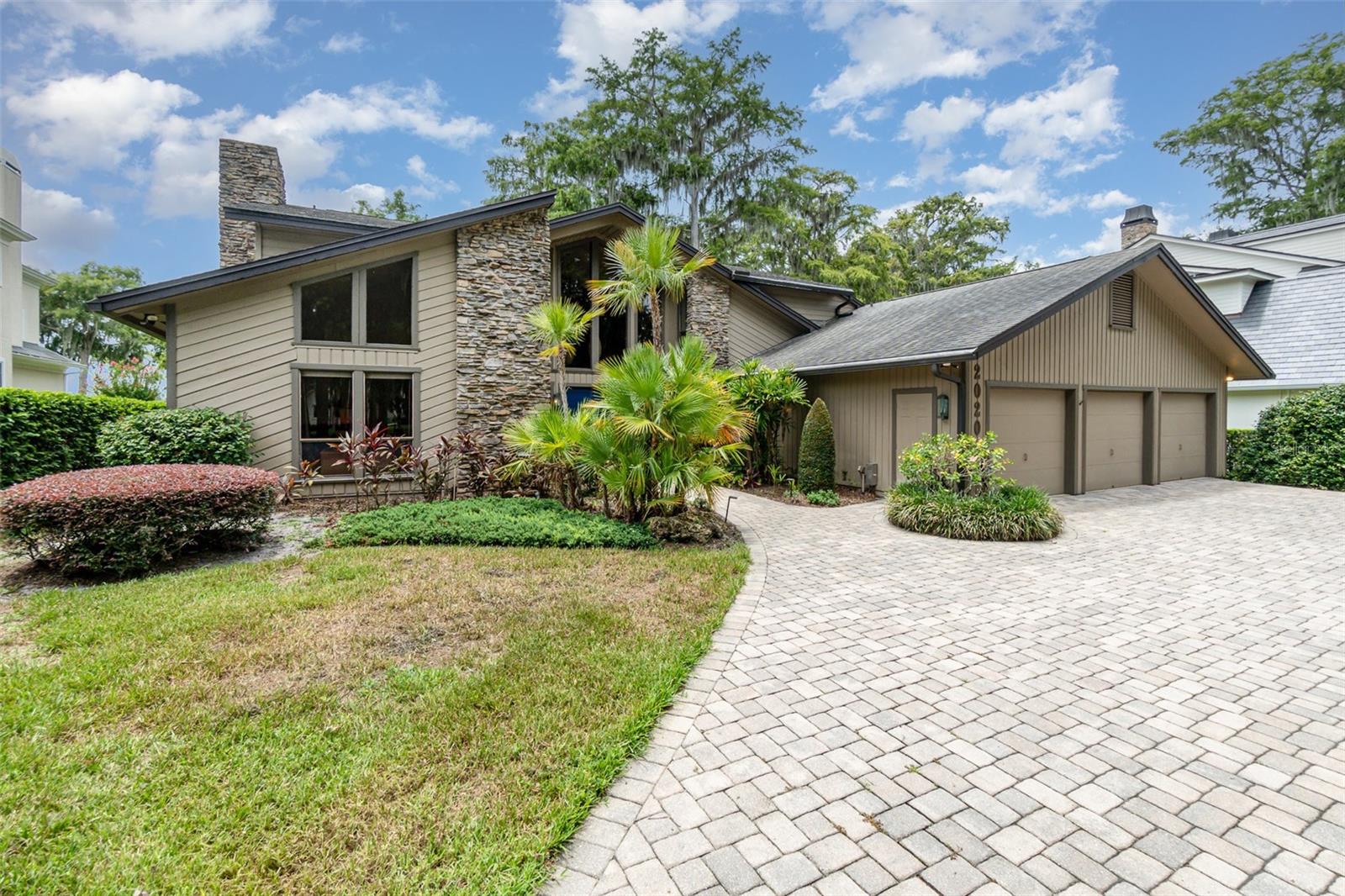 This RARE LAKEFRONT retreat is located on a quiet, tree-lined street in the highly sought-after Vias of Winter Park. Custom-built and elevated on a prime lot with 90 feet of frontage on Lake Maitland, this one-of-a-kind mid-century home offers sweeping views of Lake Maitland and the Isle of Sicily. It combines timeless design, complete privacy, and a premier location just minutes from Park Avenue and the Winter Park Racquet Club.
With over 4,100 square feet of living space, the home features 4 bedrooms, 3.5 bathrooms plus an office. Inside, rich wood accents, teak and cedar ceiling details, and impressive stone fireplaces create warmth and character. A sunken conversation area with stone fireplace anchors the main living room. The kitchen includes a center island, ample storage, and a separate breakfast area. It overlooks the water and opens to a cozy family room with a vintage custom bar and fireplace, perfect for entertaining.
A large screened porch stretches across the back of the home and provides the ideal space for year-round relaxation. Enjoy quiet mornings with birdsong and panoramic views of the manicured backyard and the lake.
The first-floor guest suite has its own private en suite bath. Upstairs, two additional bedrooms share a hallway full bath. The large primary suite offers breathtaking lake views, a walk-in closet, and a master bathroom with double sinks and a vanity. A separate office or flex space with built-ins adds a comfortable and private place to work.
Additional features include a 3-car garage, full laundry room, a dedicated workstation, your own private boat dock and full house generator!
Enjoy the best of Florida lake living and access to the largest lake on the Winter Park Chain of Lakes.