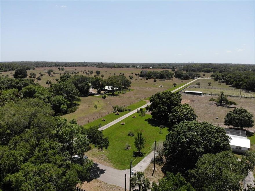 Horse and Cattle Ranch with 3 houses for sale in Fort Myers, Buckingham area. Largest privately owned land for sale in the area- 100 acres more or less. If you are looking for a family compound, this is perfect! Frontage on Orange River Road and Higginbotham Rd. Includes Three (3) Houses (est. square footage is combined) on the property with numerous barns, stables, and workshops. One home has a swimming pool with a screen enclosure. This property is surrounded by home sites with at least one acre, or more. So, you are out in the country, yet only 5 minutes from I-75 at the Hwy 80 exit. Main House—CBS construction 3 bedroom, 2 bath with Screened porch, 3-truck-sized parking carport, Large 60x45 Workshop with Screened breakroom with kitchenette and bathroom, Horse Stable with 2 stalls, Horseshoe game pits, Tire Swings from huge Oak Tree. House #2—CBS construction 3 bedroom, 2 bath with screened back porch, Metal Roof and paved parking areas, large water system, Pole Barn 25x60x12h Workshop 30x65, Large Oak Trees. House #3 CBS with Swimming Pool, Metal Roof, Carport, circular drive, Road Frontage on Higginbotham Rd. There is a LIGHTED ARENA for night-time training, with an observation tower and a calf-roping shoot.  Several wells provide water for horses, and cattle, along with residential use. There are even dog kennels (needs some work) for the avid dog lover. This area of Lee County is in a Rural Community Preserve designation, which means the country feel will be maintained and not over-developed. In fact, there is a probable investment aspect to subdividing this into one-acre homesites, if someone wanted to pursue that in the future.