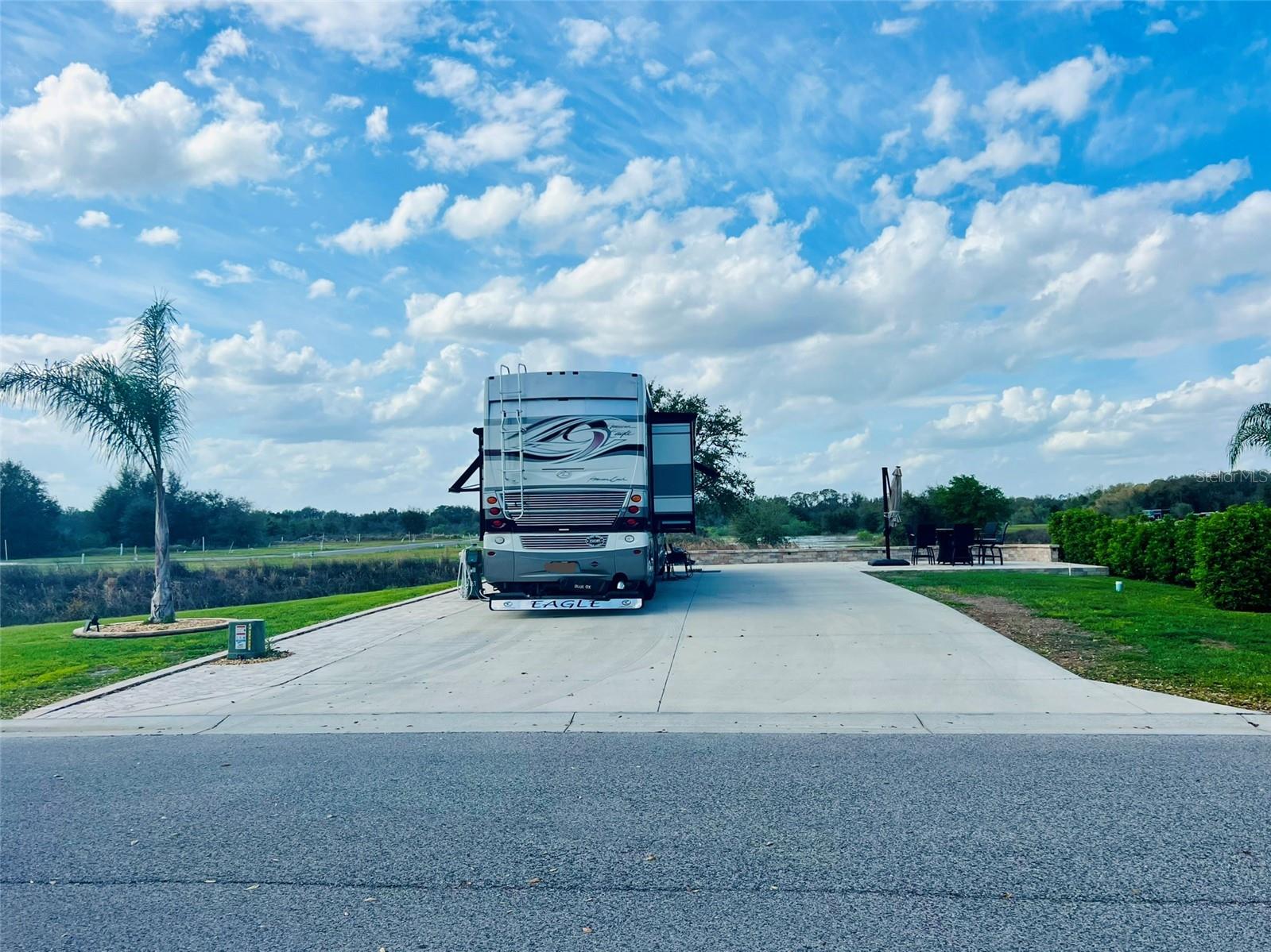 Lot 478 at Florida Grande Motor Coach Resort is a rare gem in the resort’s Phase 2 expansion,
offering an expansive north-facing pull-in lot with stunning pond views. This property
spans over 5,000 sq ft and features a 26’x76’ concrete pad with 50-amp electricity, water, and
sewer at the pedestal. In-ground irrigation keeps the landscaping lush, including a beautiful
queen palm at the front. Pavers extend along the pedestal side and continue in front of the pad,
creating a spacious outdoor living area complete with a seating wall and a 12’x16’ patio—perfect
for enjoying front-row views of blue winged teals, little blue herons, and pie billed grebes on the
water. A generous community space on one side adds to the sense of openness. There’s even
room to add a 384 sq ft Grande Suite for extra comfort and functionality. As an added bonus, this
lot comes with a brand-new counter-height table with a built-in firepit and six matching swivel
stools, along with a cantilever umbrella for shade. Every detail of this lot has been designed for
both beauty and function, making it a true showstopper.
Florida Grande is the ideal home base for exploring all that Central Florida has to offer, located
just an hour from Orlando, Tampa, and Ocala, and only 90 minutes from both Atlantic and Gulf
Coast beaches. Crystal River, famous for its manatee sightings, is just a short drive away. The
resort itself is known for its strong sense of community, with an active social calendar and events
throughout the winter season. As a gated Class A and Super C resort, Florida Grande offers
incredible amenities, including a 20,000 sq ft clubhouse, pool, hot tub, fitness center, library,
billiards room, craft room, dog park, and a brand-new 8-court pickleball complex. Plus, you have
the option to rent your lot when you’re not using it for passive income. Don’t miss out on this
one-of-a-kind opportunity—schedule a visit today!