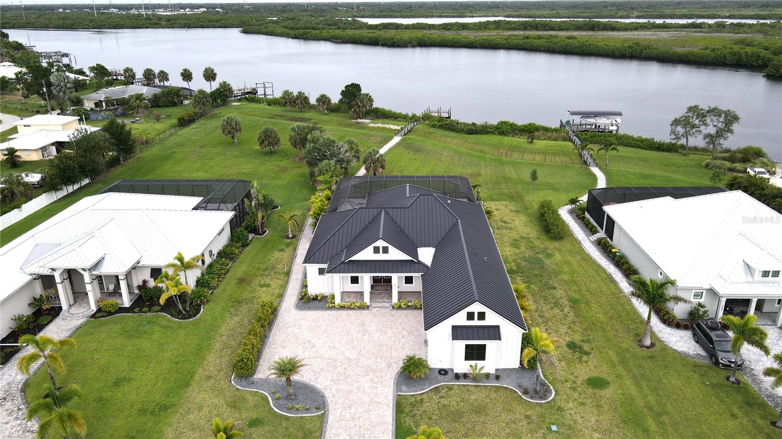 **PLEASE ENJOY THE 3D INTERACTIVE VIRTUAL TOUR ASSOCIATED WITH THIS LISTING – Welcome to Punta Gorda, Florida, and the gated community of The Estates on Peace River, comprised of only 28 homes! This new custom-built pool home enjoys approximately 140 feet of water frontage and a private dock. The house is situated on one of the larger lots in the community, measuring ~1.17 acres in size. At almost 2900 square feet, the home sports four spacious bedrooms, an office/den, three full baths, a great room with a decorative accent wall and a coveted three-car attached garage. The many custom features of this home include a neutral décor with a beamed great room ceiling, porcelain tile flooring (except for the bedrooms having wood flooring), tray ceilings, crown molding in many rooms, beautiful 8' single-panel doors and 5" base trim. The designer kitchen features stone counters with a decorative backsplash, custom GE Café appliances, including a 4-door refrigerator, wine fridge, built-in oven and microwave. The tall, solid wood cabinetry has upper glass cabinets with accent lighting. There is also an oversized custom concealed walk-in pantry. This residence also offers abundant interior storage by the laundry, a propane-fed instant hot water system, and dual-zone climate control. The open floor plan has a split bedroom layout for privacy, with a roomy Primary retreat that boasts an en-suite bath with his and her sinks, a makeup vanity, an impressive seamless glass-framed shower, a walk-in shower with dual shower heads and a large custom-designed walk-in closet. The house has an oversized paver-stone driveway and a massive rear screened pool enclosure, also adorned with pavers. The lanai enclosure has a custom wood ceiling, a heated saltwater pool with a lounging platform and an integrated hot tub. This is a perfect place to enjoy the serene river and greenbelt view. The house has highly efficient PGT impact windows and doors, a 24-gauge metal roof, underground utilities, a private composite dock with a paver stone walkway and public water and sewer connections. The Estates on Peace River is in a master-planned community of just 28 .9+ acre parcels, each with an assigned boat dock and access to the community boat launch and tiki hut pavilion. The community has a modern "coastal" motif and offers an old Florida lifestyle while providing ultra-convenient rural living with a modest monthly association fee. The Estates on Peace River has convenient access to all Southwest Florida offers by land or water. The home is 1 mile from Charlotte County Emergency Services, 3 miles from shopping, 8 miles from Interstate 75 (exit 164) and 10 miles from historic downtown Punta Gorda and the Punta Gorda Airport (PGD). Take a virtual walk-through by clicking on the provided link, then arrange your in-person visit to experience The Estates on Peace River for yourself! The seller is highly motivated!