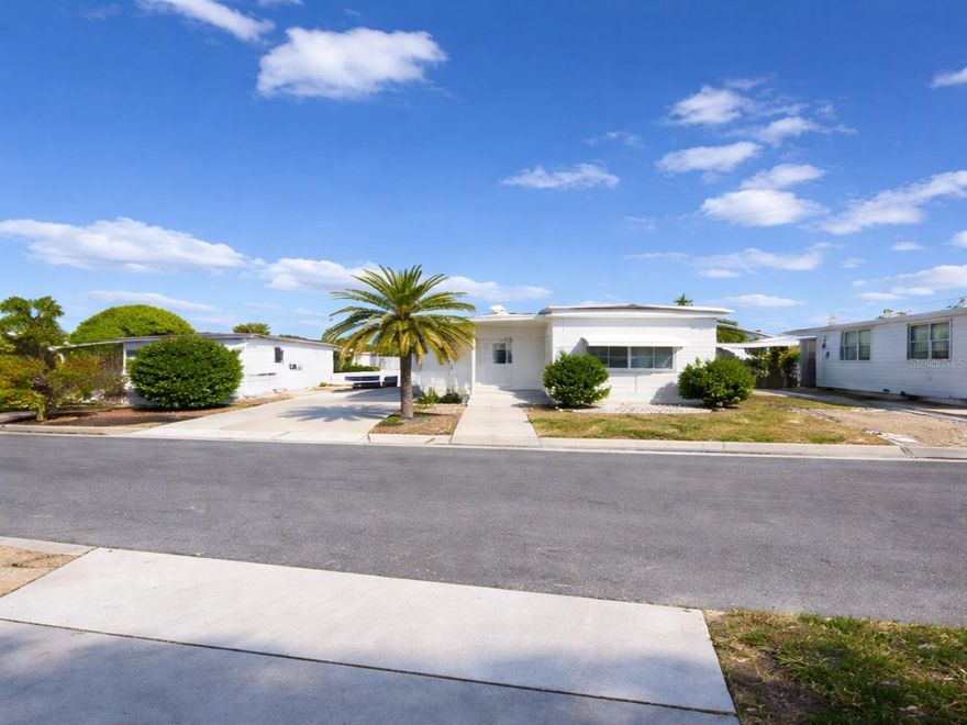 This mobile offers excellent value with a low $105 monthly HOA fee covering trash, water, and lawn care. Tropical Gardens is a 55-and-older cooperative community. This unit includes one share in the coop valued at over $20,000.00. The unit has two bedrooms and one bath with a large living room, open kitchen, and dining area. The washer and dryer are indoors, right off the hall on a porch. All rooms are furnished except one bedroom. Low-maintenance roof over, central heating, and a window air conditioner. Convenient for shopping, medical, and restaurants. A quick 20-minute drive to St. Pete Beach, Madeira Beach, and the VA Medical Center. In beautiful St Petersburg, few places offer such value. This is a Cash sale only.  Pet Policy: 1 Dog to 35lbs (Emotional Support Only)