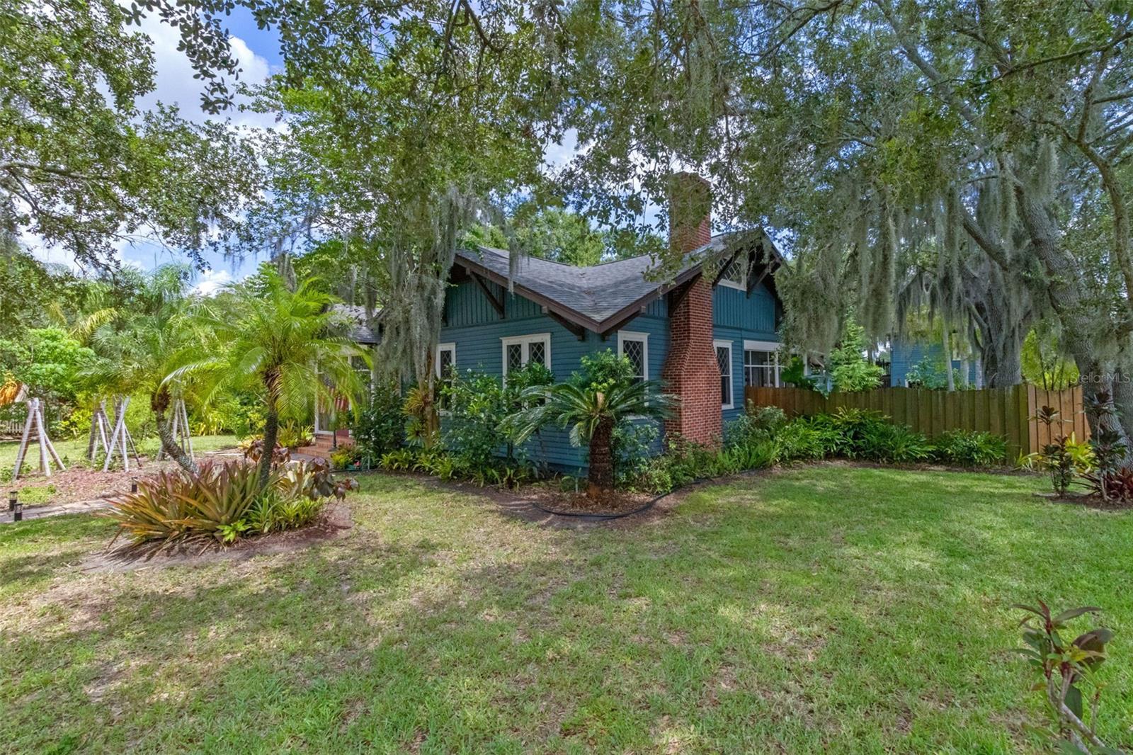 Step back in time and experience the timeless charm of one of the original homes in Lake Wales, lovingly maintained and thoughtfully preserved since its construction in 1915 by renowned local craftsman J.F. Townsend. This distinguished Arts and Crafts Bungalow stands as a testament to the area’s rich architectural heritage and offers an unmatched opportunity to own a piece of local history.
Set on a generously sized corner lot shaded by majestic oak trees and surrounded by mature landscaping, the property offers a serene escape just steps from Downtown Lake Wales and a short walk to Lake Wailes, where you can enjoy scenic walks, birdwatching, or peaceful reflection by the water.
From the moment you arrive, the character of this home is undeniable. A welcoming screened front porch offers front-row views of community events and parades along Central Avenue. Inside, the living room features six large diamond muntin windows that fill the space with natural light, original hardwood parquet flooring, a field tile wood-burning fireplace with carved mantel, crown molding with picture rail, and a stunning antique arts and crafts chandelier.
Historic charm continues into the dining room, which is accessed through arched pocket doors with beveled glass. A second screened porch off the dining area provides a private, tree-lined escape. The home includes three bedrooms, each with its own ensuite bathroom. The primary suite, located at the rear of the home, offers privacy, an expansive wall of closets, and a tranquil screened porch overlooking the pool and original orchid house. Another bedroom features a unique sleeping porch with windows on three sides, currently serving as a cozy den and home office.
Beyond the main home lies a detached two-car garage with a full apartment above, complete with a kitchenette, full bath, and bedroom—ideal for guests, in-laws, or rental income. The original orchid house, now a versatile pool house or creative studio, is air-conditioned and includes a half bath, perfect for entertaining or working from home.
A large pool and surrounding deck offer the perfect backdrop for outdoor gatherings, while multiple screened porches invite you to relax and enjoy views of the beautifully manicured grounds. Additional features include a whole-house attic fan, spiral staircase to a massive walkable attic, and the unmistakable feeling of a home that has been deeply cared for over generations. Main home roof replaced March 2023.
This is more than just a home—it’s a piece of Lake Wales history, beautifully preserved and ready to be enjoyed for years to come.