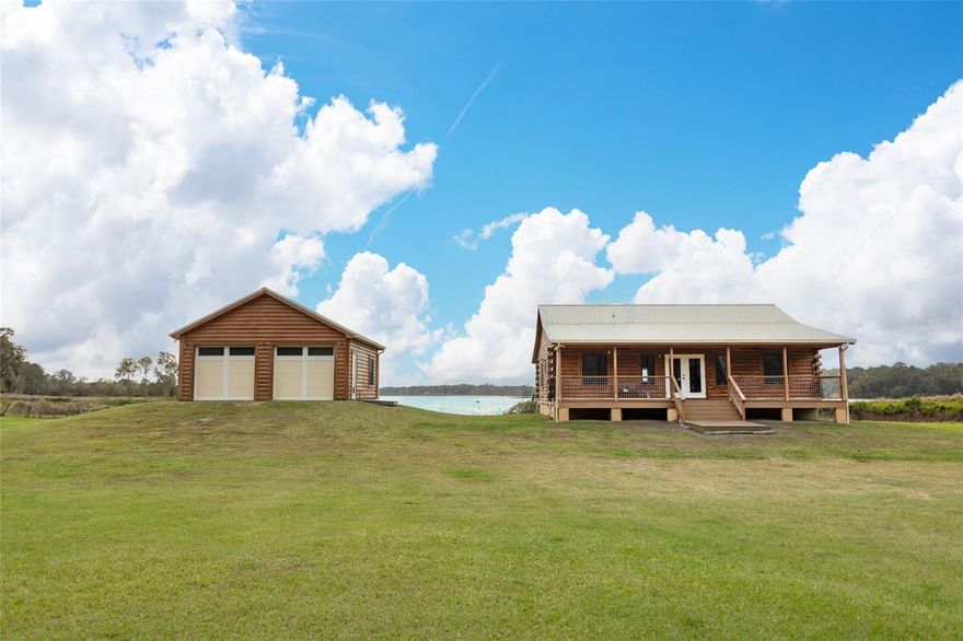 Peace, Tranquility and Nature. This is the perfect location to raise a family or spend your days enjoying the country. Five acres of cleared land which is also fully fenced on Lower Lake Louise. Enjoy your modern crafted log cabin home built in 2022. The interior of the home has vinyl flooring throughout, 18 foot ceilings and plenty of room to enjoy family gatherings. A gas fireplace is perfect for those cool winter nights. The kitchen has new Samsung appliances, a gas stove, large kitchen cabinets and a kitchen Island with Marble countertops and counters. The front and back porches are Trex decking with plenty of room to sit and enjoy the lake views or watch the children play. The house and garage have Anderson Impact low energy gray glass windows, Fiberglass impact low E exterior doors, a metal roof and spray foam insulation. The garage is a two car 24x24 air conditioned space with a epoxy floor finish that can store your collectible cars, can be used as a workshop or as a separate craft room. The garage doors are Clopay impact insulated doors with WiFi remote access. A propane tank and gas line are for the generator, outdoor grill, indoor fire place, stove and dryer. This property also includes the right to have a small secondary trailer on-site that can tap into the shared well and septic system. Enjoy your day fishing and you can also add a dock in the future to store your boat and Kayaks. Only a short drive to Crescent City, Bunnell and just 45 minutes to Flagler Beach. Visit Orlando for the day which is 60 minutes away. Call me today to view this Seville country estate.