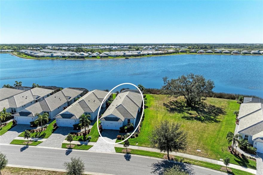 Set along the tranquil shores of Lake Ibis, this exceptional lakefront residence showcases spectacular, long, uninterrupted water views and breathtaking sunset vistas that define true Florida living. Built in 2022 by Homes by Towne, the Skiff floor plan offers thoughtful design, quality construction, and an enviable waterfront setting. Spanning 2,158 square feet, the home features three bedrooms, two full baths, a dedicated office/den, and an open-concept layout designed to maximize natural light while framing the stunning lake views from multiple living areas. The kitchen is both stylish and functional, featuring quartz countertops, custom cabinetry with soft-close drawers and pull-out shelving, under-cabinet lighting, stylish backsplash, and a layout ideal for everyday living or elaborate entertaining. The great room opens seamlessly to an extended lanai with a full-view screen enclosure, preserving clear sightlines across the water and front-row views of vibrant sunsets. The outdoor living area is a true highlight, offering a pool, separate standalone spa, generous covered seating area, an ideal setting for morning coffee overlooking the lake or evening gatherings as the sun sets aglow with color over the water. The owner’s suite is positioned to capture serene water views and glowing sunsets, creating a peaceful retreat complemented by a spa-inspired bath with dual quartz vanities, and upgraded finishes. Two additional bedrooms and full bath on the other side of the home provide private flexibility for guests or family, while a light-filled office offers a quiet space for work or hobbies. Additional features include a large laundry room and a two-car garage with epoxy flooring and storage. Residents of LakeHouse Cove enjoy resort-style amenities, including a pool and spa, state of the art fitness center, clubhouse with catering kitchen, boathouse with kayak launches, pickleball courts, fire pits, dog parks, and a full calendar of social activities. Be as social as you want within this community.  Conveniently located just minutes from Waterside Place, Lakewood Ranch Main Street, University Town Center, and downtown Sarasota, this exceptional residence offers effortless access to world-renowned beaches, celebrated cultural attractions, and Sarasota-Bradenton International Airport. A short journey opens the door to Florida’s iconic theme parks, adding yet another dimension to the lifestyle. This is a rare opportunity to enjoy spectacular lake views, unforgettable sunset vistas, and the peace of mind that comes with newer construction, all within one of Lakewood Ranch’s most sought-after communities.