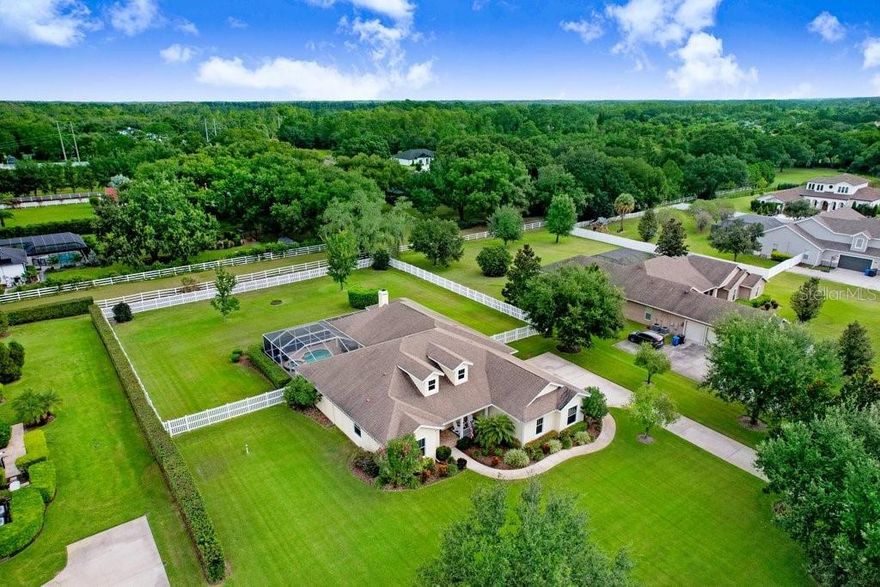 Welcome to this stunning residence in the heart of Odessa, set on a FULL ACRE in the private, gated enclave of Keystone Meadows. Perfectly positioned on a peaceful conservation lot with a fully fenced backyard, this 4-bedroom, 3-bathroom estate with a 3-car garage offers over 3,250 square feet of living space designed with elegance, comfort, and functionality in mind. From the moment you arrive, the curb appeal sets the tone—lush landscaping, stately elevation, and a spacious driveway that welcomes you home. Step inside and you’ll immediately notice the details that make this property exceptional: beautiful birchwood floors throughout the main living areas, wood-look tile flooring in the bedrooms and office, crown molding, double tray ceilings, and designer finishes that balance timeless sophistication with inviting warmth. A dedicated office provides a quiet retreat for work or study, while formal living and dining rooms create the ideal setting for hosting family gatherings or elegant dinners. The heart of the home is the expansive family room, where custom built-ins and a cozy fireplace anchor the space. Large sliding glass doors allow natural light to pour in and open directly to the lanai and pool area, blending indoor and outdoor living seamlessly. The gourmet kitchen is both functional and impressive, featuring granite countertops, soft-close cabinetry, Frigidaire and KitchenAid stainless steel appliances, double ovens, convection cooking, a Blanco granite sink, a Scotsman ice maker, breakfast bar seating, and a walk-in pantry. A sunny dinette area overlooking the pool is perfect for casual meals while enjoying serene views of the conservation lot. The luxurious primary suite is a true retreat. With private pool access, two spacious walk-in closets, and a spa-like bathroom complete with dual vanities, granite countertops, a soaking tub, separate walk-in shower, and a private water closet, this suite offers comfort and privacy. Three additional bedrooms provide flexibility for family or guests, and a convenient pool bath with direct lanai access enhances functionality. Step outside to your private backyard oasis. The screened-in, heated pool and spa with a spacious covered lanai and ceiling fans invite year-round enjoyment. Surrounded by tropical landscaping and conservation views, the backyard is perfect for entertaining friends, hosting summer gatherings, or simply enjoying quiet evenings outdoors. With the property spanning a full acre, there’s ample space for play, pets, gardening, or future enhancements. Additional highlights include a whole-house water filtration system, 2020 pool pump, and a laundry room complete with cabinetry, utility sink, and LG washer/dryer. Keystone Meadows offers the security of a gated community, while Odessa itself is known for its tranquil setting and excellent location. Families appreciate the proximity to highly rated schools, and the community is just minutes from shopping and dining at Citrus Park Mall, as well as quick access to the Veterans Expressway for an easy commute to Tampa, the airport, and surrounding areas. Combining a serene one-acre lot with elegant design, modern upgrades, and resort-style outdoor living, this home captures the very best of Florida living.