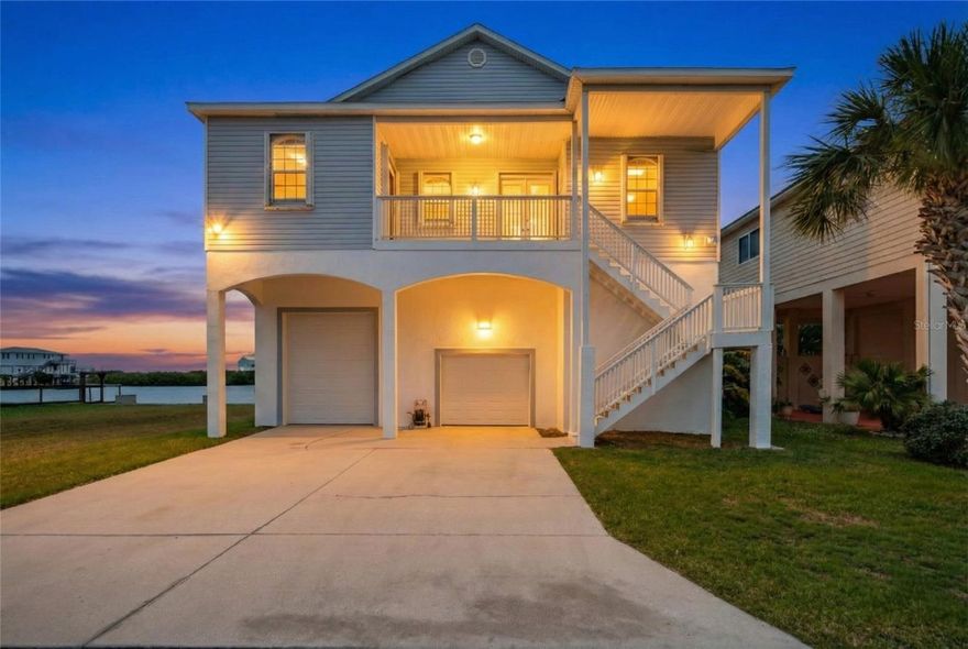 Elevated Gulf-access waterfront home in Driftwood Isles with panoramic sunset views, private elevator and exceptional garage space. Positioned on a wide water basin in Driftwood Isles with direct, unobstructed access to the Gulf of Mexico, this elevated custom waterfront home offers panoramic sunset views, natural buffering, and water visibility from nearly every living area. Built in 2001 by the current owner and meticulously maintained since construction, the property combines durable coastal construction with a peaceful waterfront setting designed for boating, storage flexibility, and enjoyment of the water. No HOA. The elevated design is a major advantage for waterfront buyers seeking practical flood-zone positioning. The main living level sits well above grade, while the expansive garage and storage areas below provide exceptional utility. Hurricane shutters and panels, dual whole-home electrical shutoffs, upgraded electrical components, and a Goldline whole-home surge protection system add confidence for coastal ownership. Inside, soaring vaulted ceilings ranging from approximately 10 to 16 feet and expansive windows maximize natural light and frame open water views throughout the home. A double-sided wood-burning fireplace connects the great room and primary bedroom. The home offers approximately 1,800 square feet of heated living space with 3 bedrooms and 2 bathrooms. A private elevator with approximately 750-pound capacity services the home, while a spiral staircase provides additional access from the garage to the main living level. Custom wood flooring crafted from a blend of red and white oak harvested from an 80-acre wood lot in Michigan adds character throughout the interior. Below the home is approximately 1,640 square feet of garage space with approximately 20-foot ceilings and roughly 21 feet of clearance beneath the rafters, creating exceptional flexibility for vehicle storage, boating equipment, workshop space, or recreational storage. The space comfortably accommodates four vehicles while still allowing substantial room for additional functionality. Three garage doors are standard height at approximately 7 feet, while one oversized garage door measures approximately 11 feet, ideal for larger boats, trailers, lifted vehicles, or specialty storage needs rarely available in waterfront homes. Covered porches and open-air waterfront spaces are positioned to capture Gulf breezes and changing sunset skies throughout the day. The seawall features substantial concrete capping, and the existing boat lift pilings are reported to be in excellent, sturdy condition. Mechanical lift boxes are present but not currently operational. A charming waterfront cutout along the seawall creates a peaceful launch point for kayaks, fishing, or quiet moments beside the water. Recent updates include a complete HVAC replacement in 2024 with hypoallergenic filtration system, complete roof replacement in 2019, four garage doors replaced in 2024, solar-powered 80-gallon water heater installed in 2018, whole-house fan system, interior painting in 2017, and exterior pressure washing completed in January 2026. Surrounded by mature coastal habitat, the property regularly attracts dolphins, manatees, pelicans, herons, egrets, cormorants, loons, rose-breasted grosbeaks, and other native birdlife. Every evening, the basin reflects changing light and color across the water, creating a waterfront setting connected to the Gulf Coast environment.