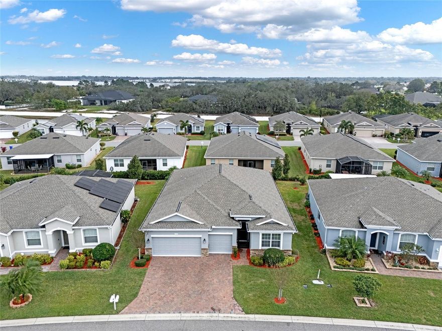 Pride of ownership shines through in this exquisite 4-bedroom, 3-bathroom home nestled within the premier 55+ gated community of Traditions at Lake Ruby. Boasting a desirable triple-split bedroom floor plan, this home features both a master suite and a junior bedroom suite with ensuite baths, offering unparalleled comfort and convenience. The generously sized great room serves as the heart of the home, perfect for entertaining guests. Enhanced with tile flooring and triple glass sliding doors, it seamlessly transitions to the screened-in lanai, extending the living space outdoors. The gourmet kitchen is a chef's dream, showcasing 42" upper cabinetry with crown molding, brushed nickel hardware, and pull-out shelves. A center island with a quartz countertop and decorative pendant lighting adds both style and functionality, while the stainless steel appliance package and walk-in pantry cater to culinary needs. Additional seating options include a charming breakfast nook and breakfast bar. Throughout the main living areas, crown molding and solid surface flooring exude elegance and sophistication. The primary bedroom suite boasts a spacious walk-in closet and wall-to-wall carpeting for added comfort. The primary bathroom is a sanctuary of relaxation, featuring a comfort-height vanity with dual sinks, a linen closet, a handicapped-accessible walk-in shower, and a luxurious garden tub adorned with decorative listello tile. This remarkable home also offers a formal dining room, a laundry room with additional cabinetry, washer and dryer, a foyer with a transom window, an in-wall pest control system, double-pane low-E windows, a keyless entry smart lock, a smart thermostat, an AO Smith hybrid water heater, and an irrigation system. Exterior features include walkway and driveway with decorative pavers, a screened-in front entrance, stone exterior facade, a roof with architectural shingles, gutters, multiple garage overhead storage racks, and a 3-car garage with smart garage door openers. Residents of Traditions enjoy a plethora of amenities, including a lakefront clubhouse, a dock and boat ramp, a heated swimming pool and spa, a ballroom, billiards, meeting rooms, a library, a computer room, a craft room, a dog park, tennis and pickleball courts, basketball, bocce ball, shuffleboard, a fitness center, an aerobics studio, and much more. With its convenient location near shopping, restaurants, major routes, and Legoland, this home offers an exceptional lifestyle. Monthly HOA fees cover exterior house painting, cable, internet, lawn service, and clubhouse amenities, ensuring a worry-free living experience.