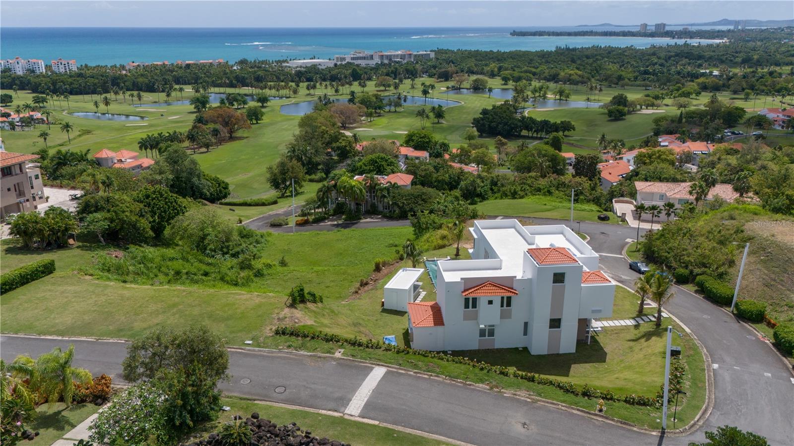 The rolling hill 29,360 square feet lot (3/4 acres) enjoys privileged views to the golf courses and ocean views within one of the largest residential lots in the Wyndham Grand Rio Mar Resort. A decorator ready contemporary residence with exclusive finishes throughout was design in a two levels floorplan with a gross area of 6,115 square foot plus a third level for an open roof terrace with 2,620 sqf. The spacious residence with ample open space living areas with high ceilings includes five bedrooms with seven bathrooms, garage for three vehicles and a golf cart. A double vault entrance opens to the living, dining and family area connected to the decorator ready kitchen area. Also, a studio/maid's quarter is located on the first level. With an authentic open concept, the indoor blend with the outdoors through floor to ceiling glass walls and doors. The outdoors includes a pool and spa, terrace, gazebo with facilities for an outdoor kitchen and bathroom. On the second level the spacious primary suite with floor to ceiling glass windows overlooking the ocean and the Rio mar Resort golf course, enjoy a private balcony, a dual vanity bath with a spacious rain and hand showers and space for a stand-alone spa tub, as well as two spacious walk-in closets. In addition, 4 large bedrooms with closets plus a private second family room. The house includes a dedicated laundry room, flex room, ample staircase with provision for a future elevator. Other features of this residence include hurricane resistant windows, water cistern and solar water heather. This private gated community situated in Rio Mar within Wyndham Grand Rio Mar Resort, a private beachfront community that provides residents privileged access to an array of desirable amenities such as two 18-hole championship golf courses, beach club, fourteen tennis courts, renowned restaurants, pools, spa, casino and other amenities with the required club membership for residents. Only a 35-minute drive from San Juan. Experience the epitome of resort living while being within proximity to San Juan. Also, near various marinas and yacht clubs including the largest in the Caribbean, El Yunque, Bahia Beach Resort, Icaco, Vieques and the American and British Virgin Islands. The best resort living in Puerto Rico.