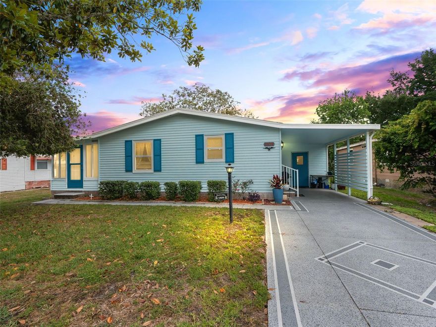 Charming FURNISHED home located in the beautiful Orange Blossom Gardens in The Villages offering wonderful curb appeal with a painted driveway, attractive exterior colors, and a covered carport. Surrounded by beautiful mature trees, this property provides a welcoming setting in a convenient central location close to shopping, restaurants, banking, and everyday conveniences.

Inside, the home features a light and bright interior with neutral colors and a spacious great room highlighted by vaulted ceilings, creating an open and inviting atmosphere. The kitchen features stone-look countertops, light cabinetry with crown molding, a stainless double sink with a window above, wood laminate flooring, ceiling fan, and an appliance package including a stainless range and hood.

The spacious dining area is conveniently located adjacent to the kitchen, making everyday living and entertaining easy and comfortable. The large great room flows seamlessly into the enclosed sunroom featuring tile flooring and floor-to-ceiling windows, providing additional living space filled with natural light.

Both bedrooms are generously sized with ceiling fans and two full closets, while the home offers a full bath for comfort and convenience. An additional storage room includes the washer and dryer along with plenty of shelving for extra organization and storage needs.

This home combines charm, functionality, and a fantastic location in one of the most desirable active adult communities in Florida. Schedule your private showing now! Golf Cart Available Separately.