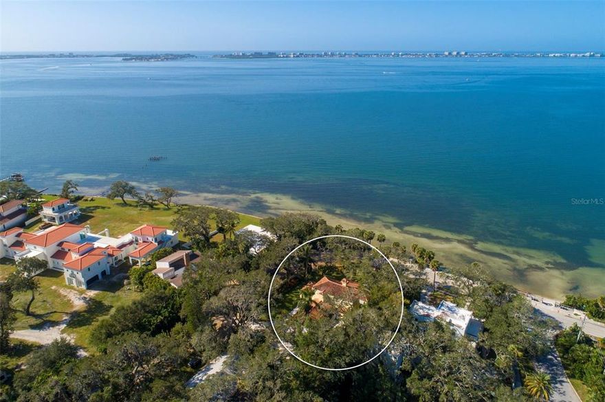 A brilliant fusion of historical beauty and modern luxuries is epitomized throughout this private home that soaks in bygone era architecture, regal comforts, and breathtaking bay views. In a park-like setting behind a stone wall and iron gates, “Splendida” evokes a kinesthesia of reverence as intentional vintage details and purposeful upgrades gracefully touch every area of this property. Built in 1923, this traditional Spanish home, listed on the National Register of Historic Places, has been meticulously cared for and improved to thoughtfully preserve its character and add an artistic twist with contemporary amenities. Spanish and clay tile floors, aluminum-finished black iron doors and Juliette balconies, stately carved columns and mantles, and solid wood doors are accentuated by high ceilings adorned in crystal and antique chandeliers, hand-painted murals, and an abundance of natural light. Intimate spaces effortlessly flow together, from the impressive foyer with arched entry to the renovated kitchen to the incredible outdoor living areas that embrace verdant gardens and bay vistas. An entertainer’s dream, the formal living room may capture the most awe-worthy view in the home with wraparound French doors facing Indian Beach and a fireplace that makes a lasting impression. Opposite the living room is the kitchen, equipped with GE Profile stainless appliances and gas stove, opulent cabinetry with blue hardware that matches the stunning cobalt blue granite countertops, and expansive island. Enjoy coffee in the breakfast nook, host special occasions in the formal dining room with magnificent cabinetry, mingle on the updated screened patio that affords incredible views and breezes, and relax with your favorite beverage on the covered and open-air patios. A den/office with half-bath is just off the foyer to manage daily tasks while the second floor features a guest bedroom, two guest baths, a third guest bedroom/media room with balcony, and the ample owner’s suite with his and hers walk-in customized closets, dressing room, and en-suite bath. The current owners have put great pride in restoring the history and essence of the property while considering today’s needs for flexible space with a large laundry room that includes plentiful cabinetry, a Florida room with built-in antique cabinetry from Paris, an elevator, restoration of the barrel tile roof with gutter screens, a finished garage with hurricane door and epoxy floor, complete replumbing and rewiring, and enough space in the backyard to include a pool. Walk beneath ancient oak trees on the property and out through the gate to the water’s edge and pier just across the street for enchanting sunsets and a timeless sense of paradise. Furnishing offered with separate contract.